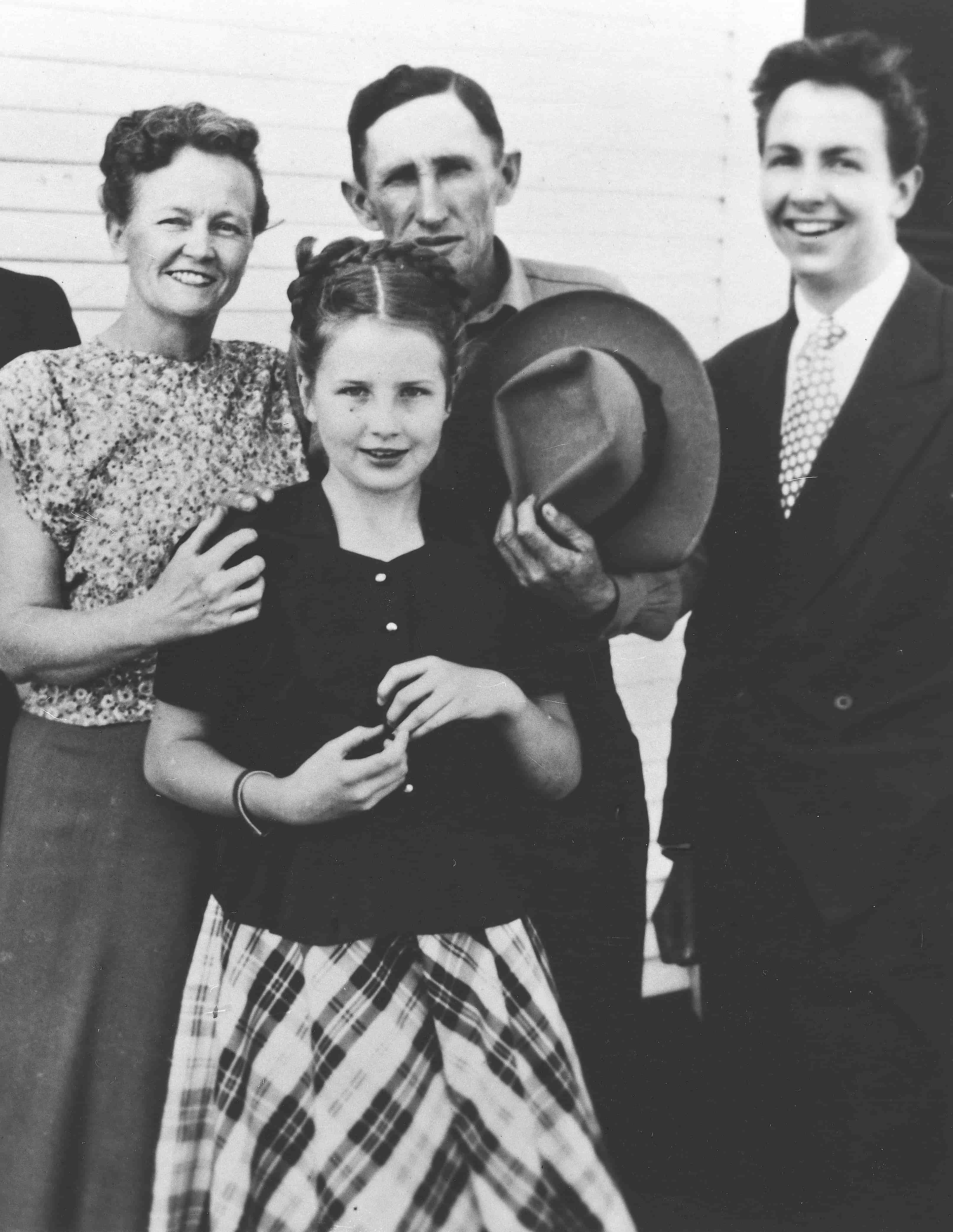 A smiling family – a woman, a man, and a young girl – pose for a photograph outdoors.