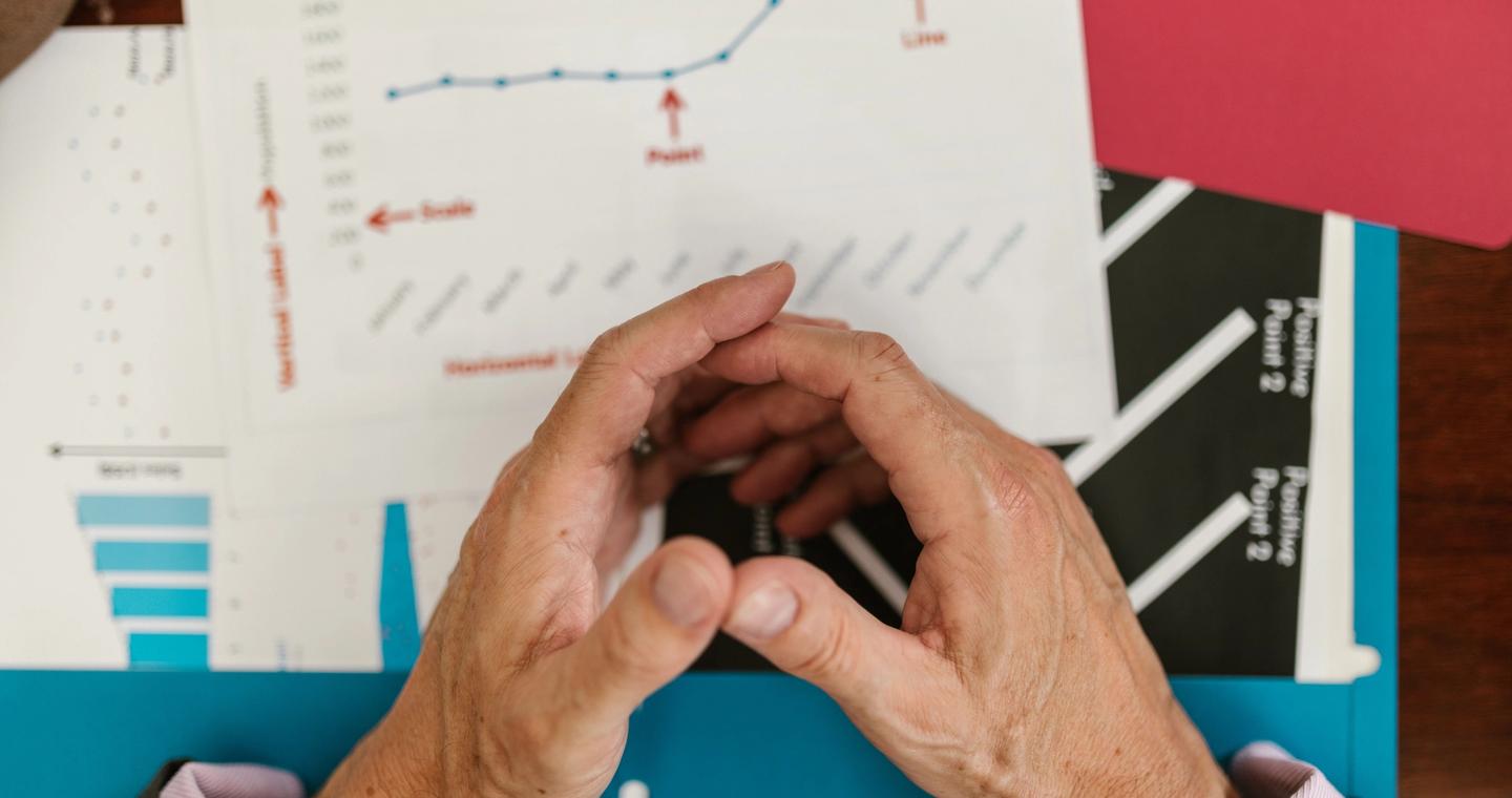 Hands reviewing printed charts on an office desk.