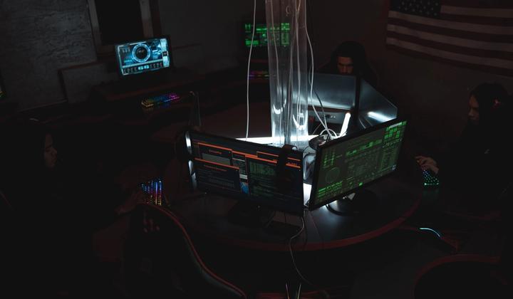 People sit at computer workstations in a dim room.