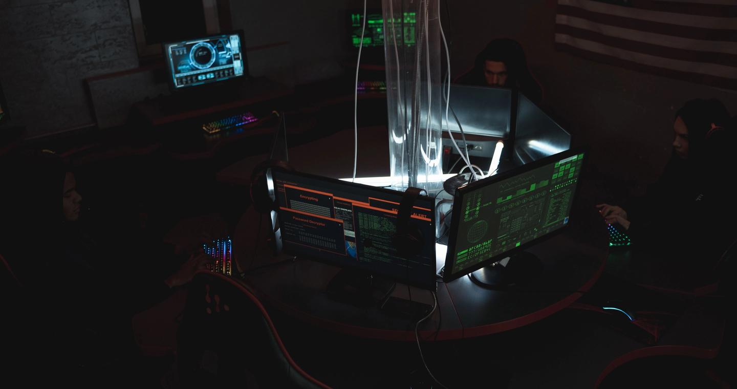 People sit at computer workstations in a dim room.