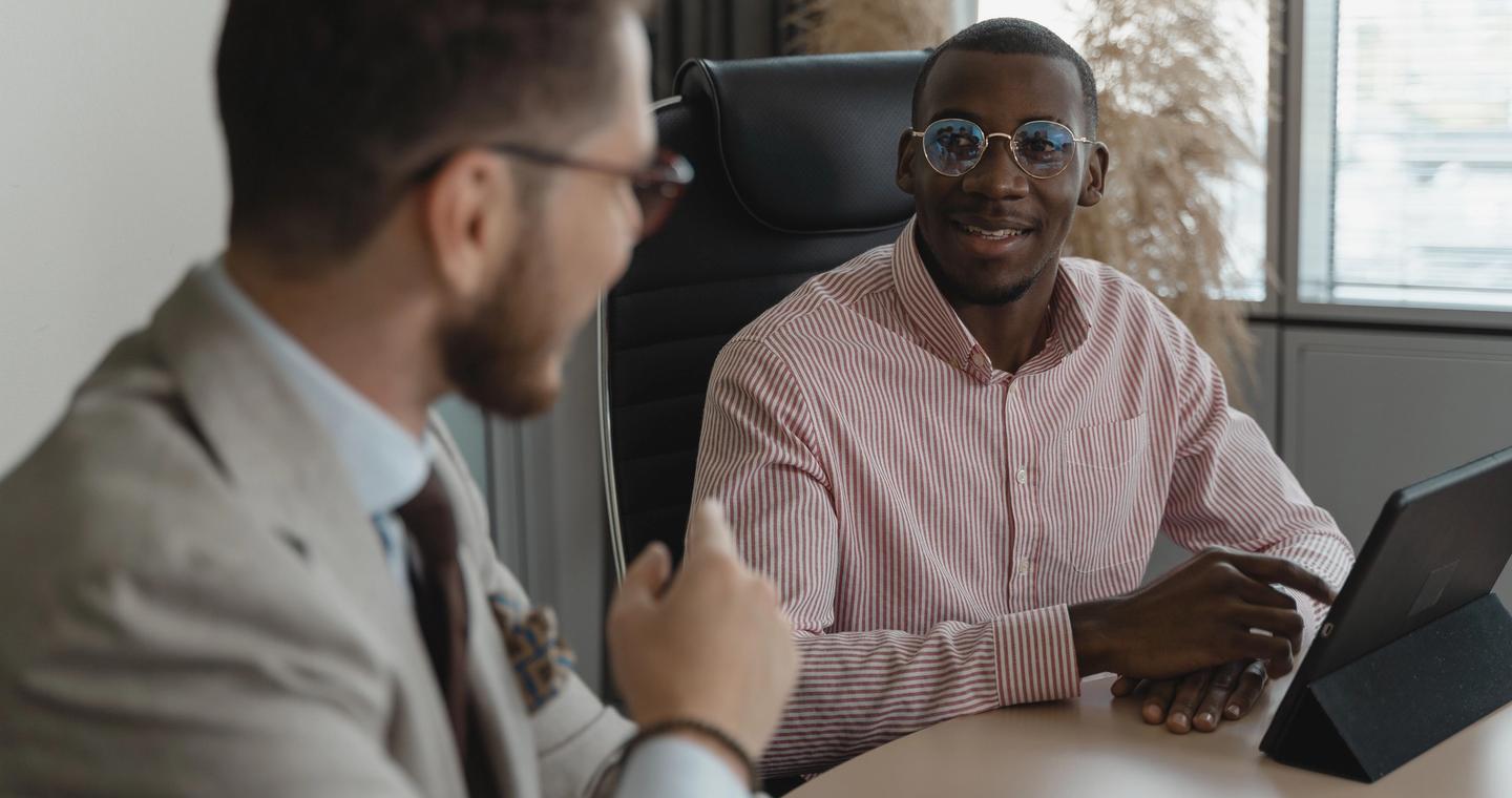 Two people talking across an office desk during an interview.