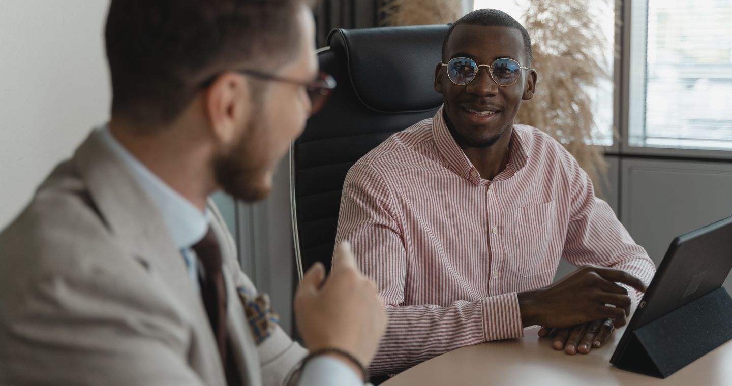 Two people talking across an office desk during an interview.
