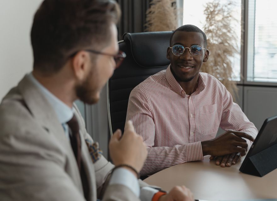 Two people talking across an office desk during an interview.