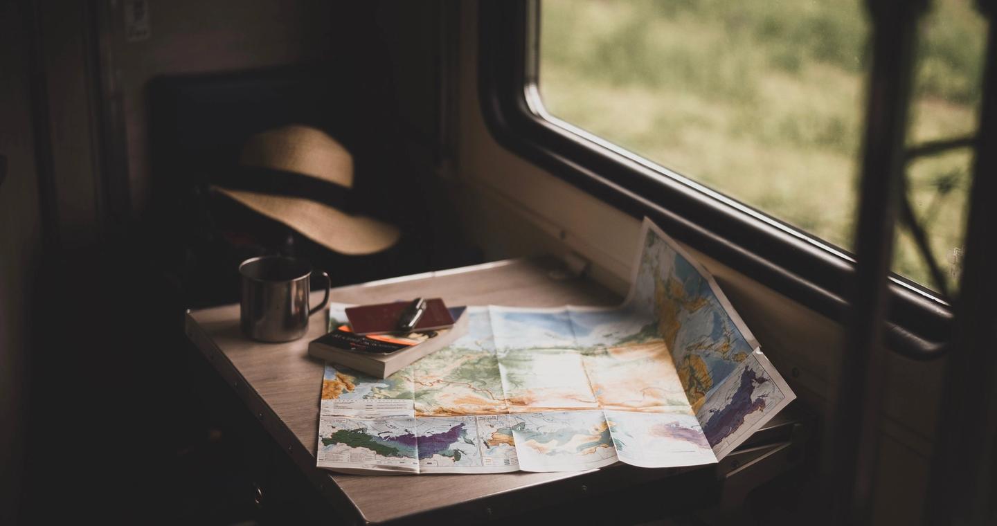 A paper map, mug and hat beside a window.