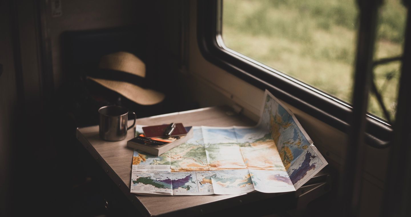 A paper map, mug and hat beside a window.