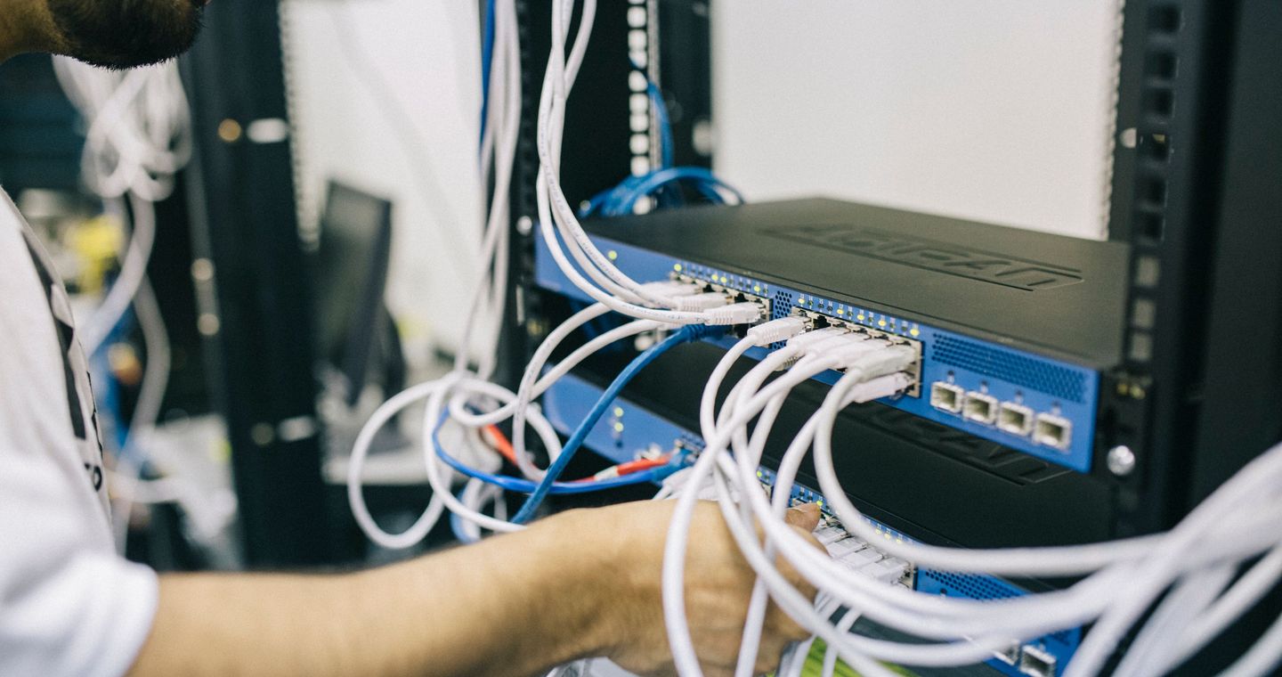 A technician adjusts cables in a server rack.