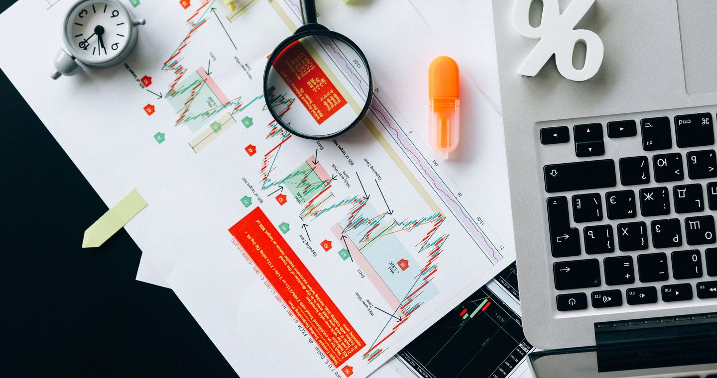 Printed charts and a laptop arranged on a desk.