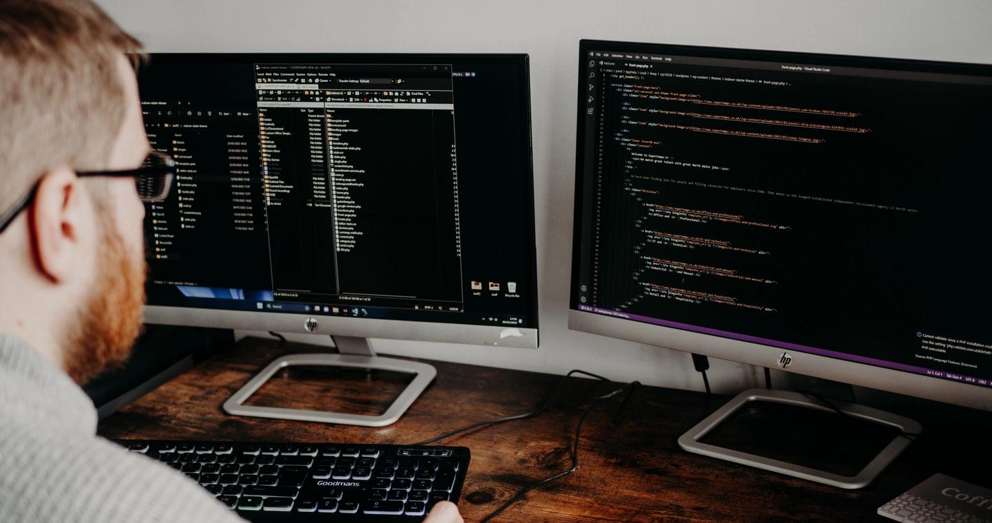 A developer using two monitors in a home office.