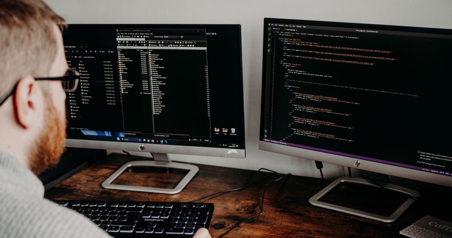 A developer using two monitors in a home office.