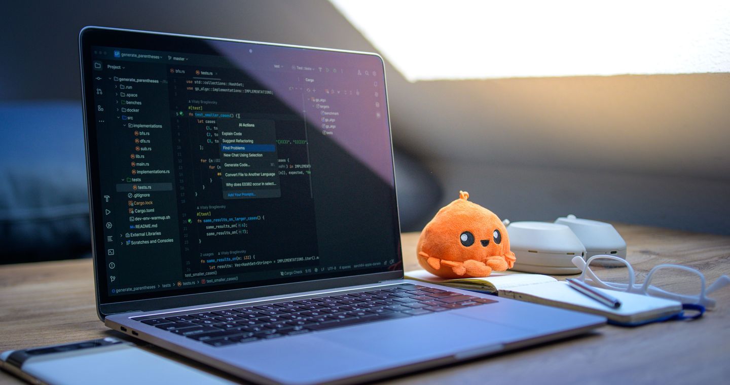 A laptop, smartphone and orange toy on a work desk.