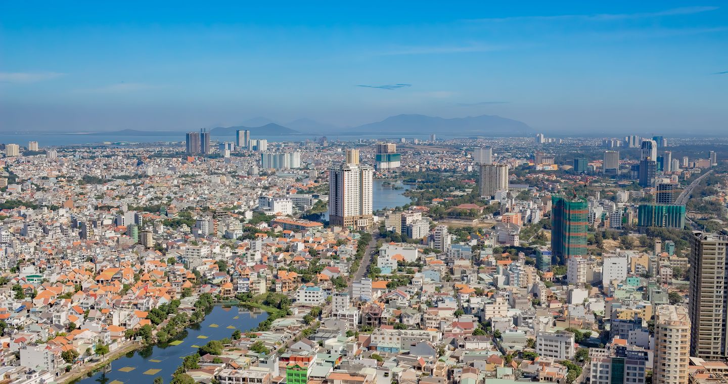 A wide cityscape with waterways and distant hills.