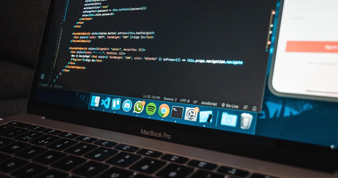 A close view of a laptop displaying code on a work table.