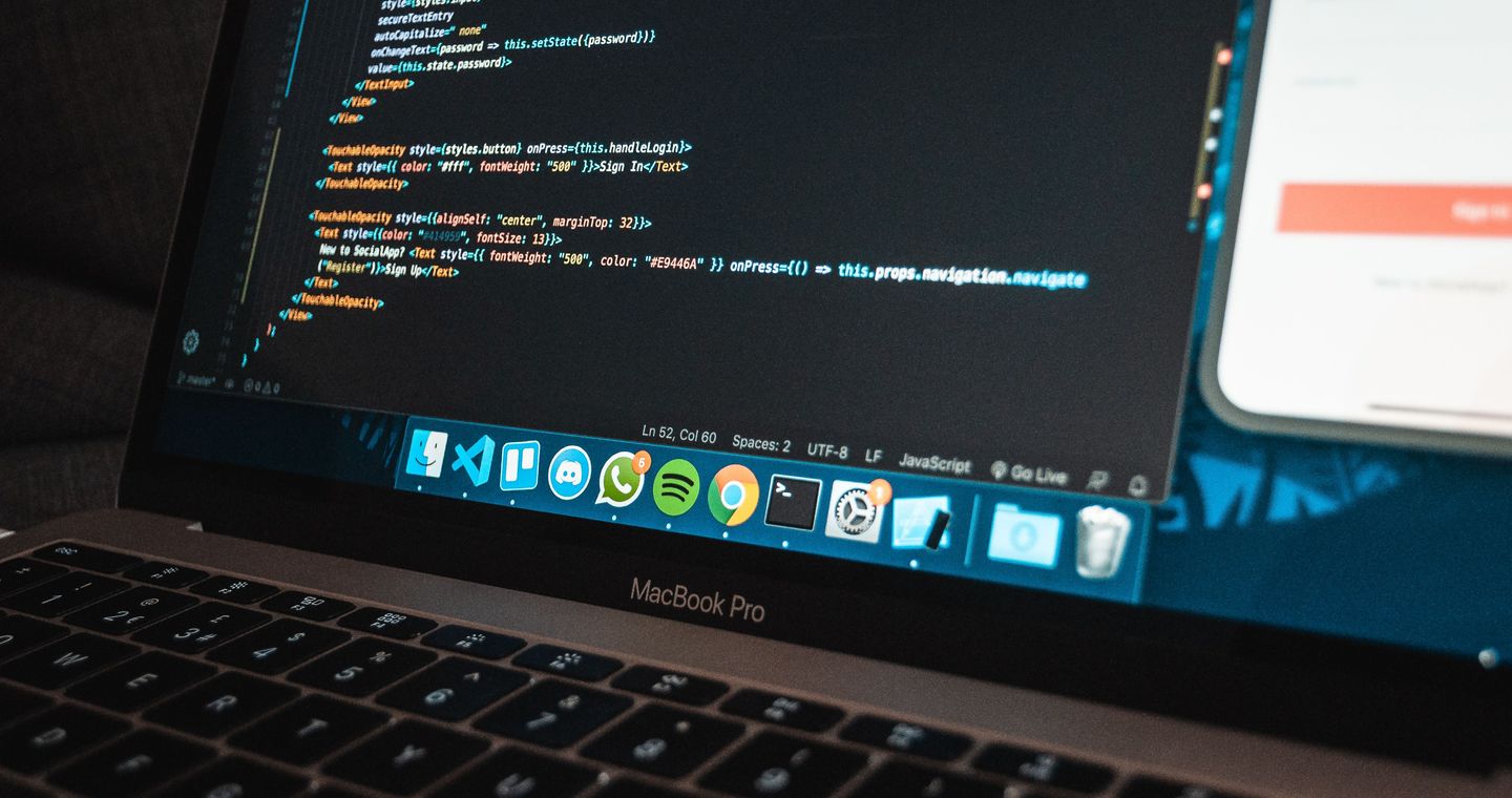 A close view of a laptop displaying code on a work table.