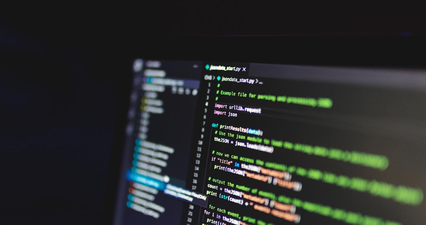 Programming code on a screen in a dark room.