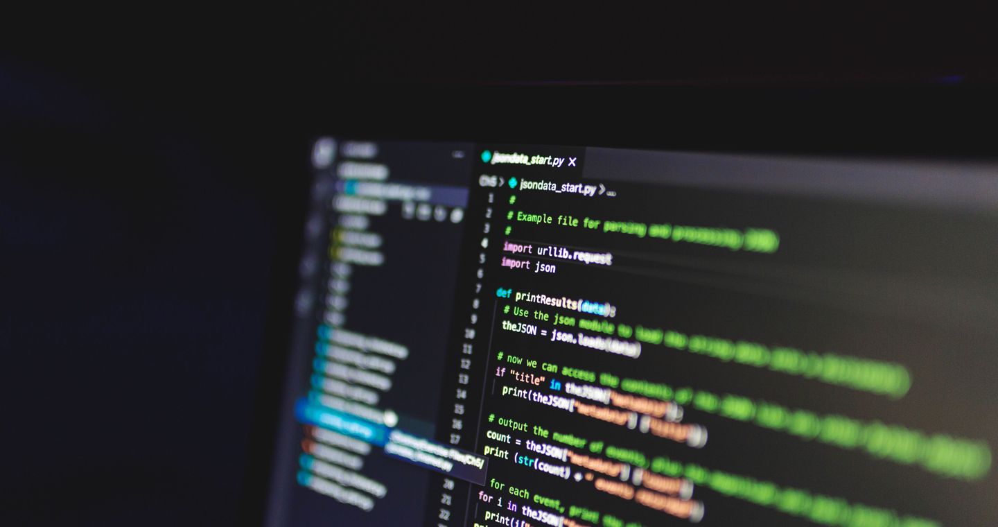Programming code on a screen in a dark room.