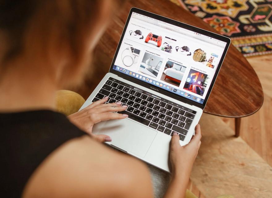 A woman browsing products on a laptop at home.