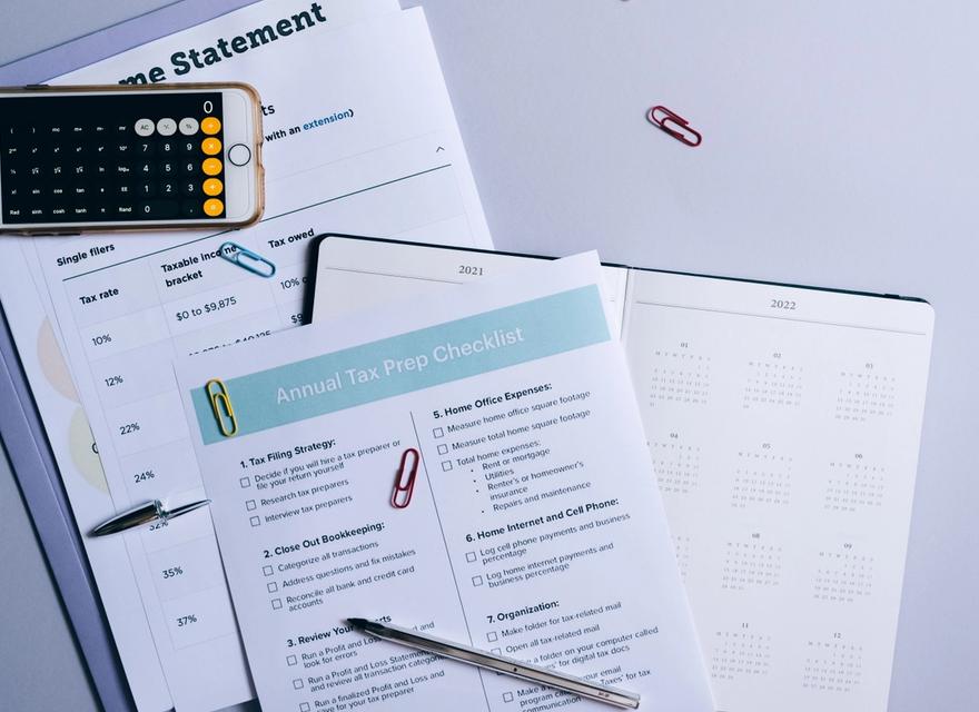 Documents, a phone, a pen and a calculator lie on a table.