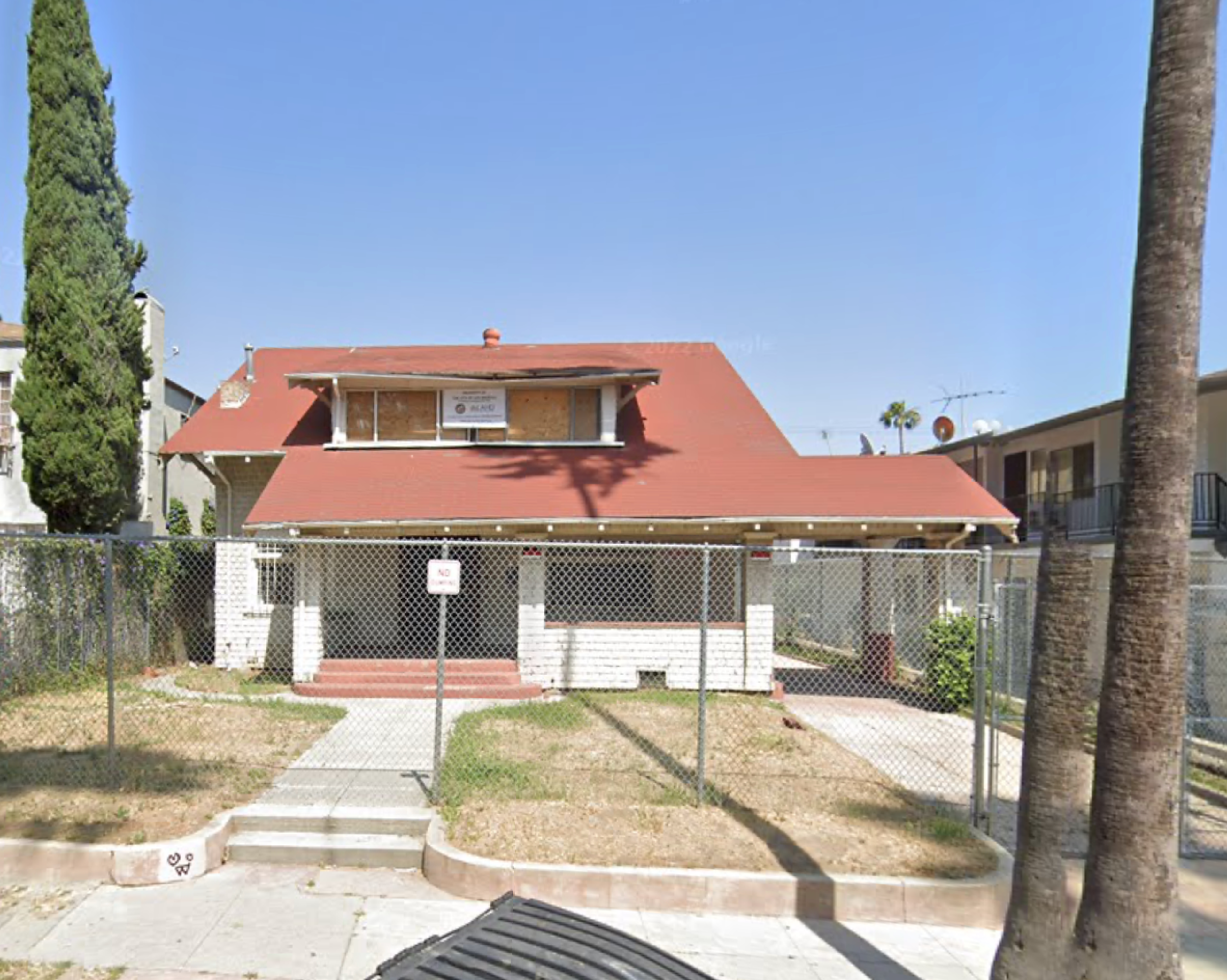 Screenshot of 1816 N. Wilton Pl., a white two-story Craftsman house with boarded-up windows, a red roof, and red front steps, before it burned down