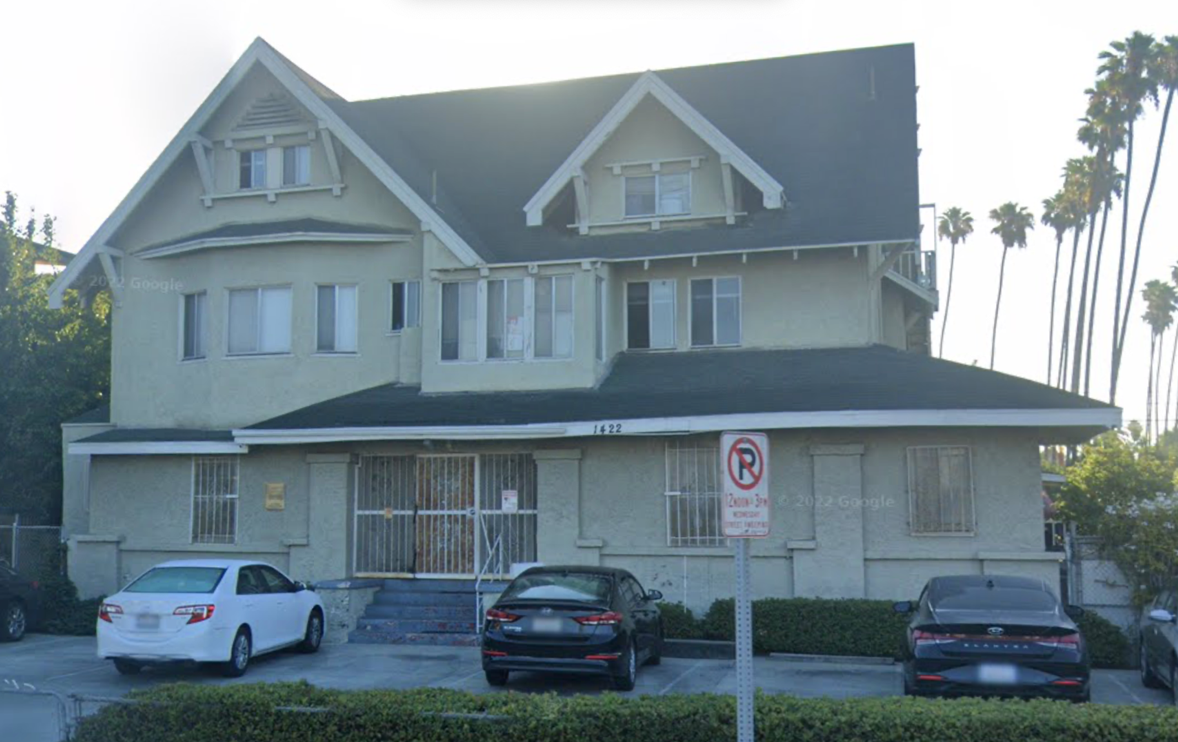 Street view capture of 1422 S. St. Andrews Place, a yellow/beige three-story Craftsman multifamily home with a gray roof.