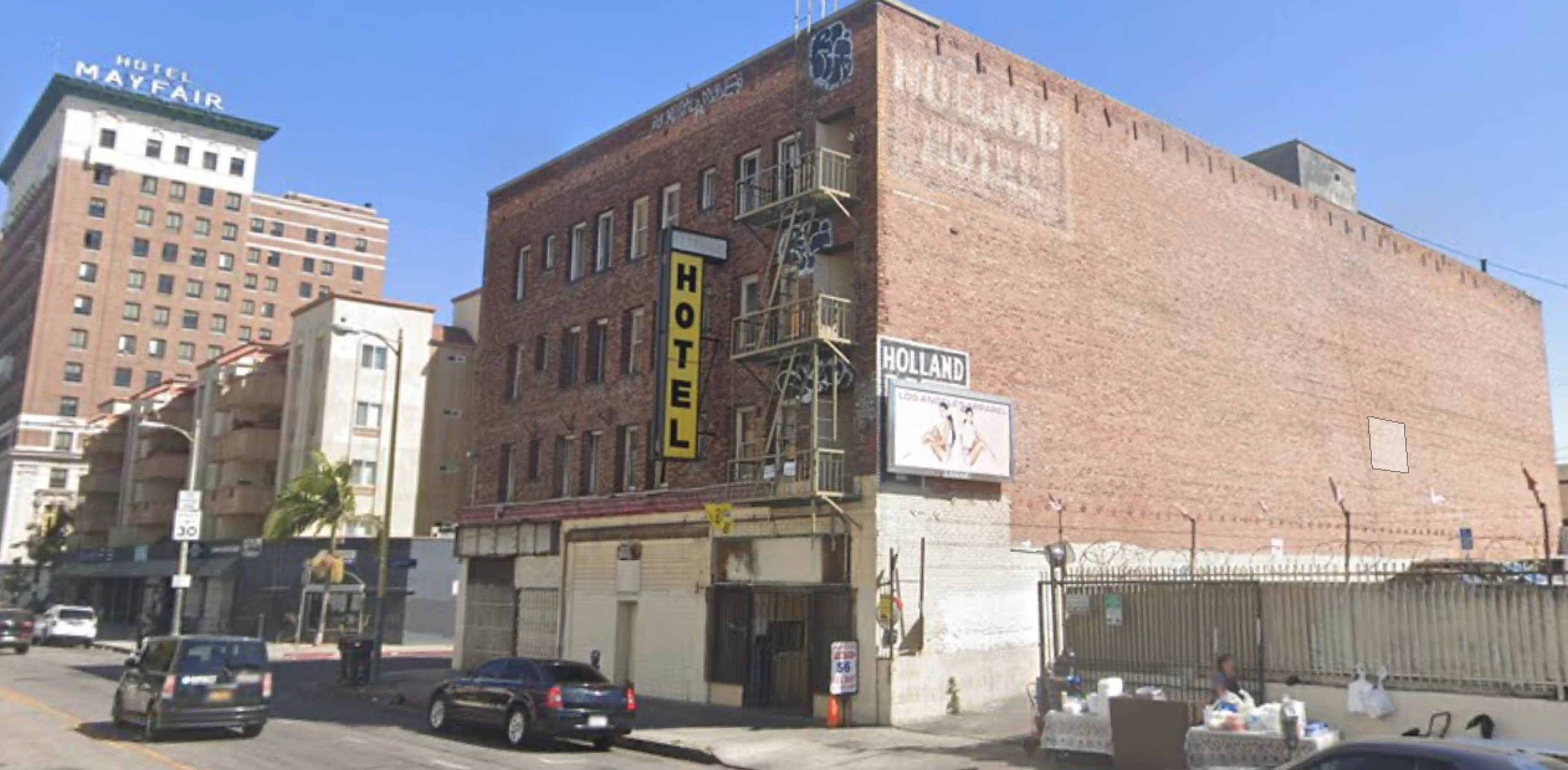 Holland Hotel, a decrepit four-story red brick building, with the nearby Hotel Mayfair in the background