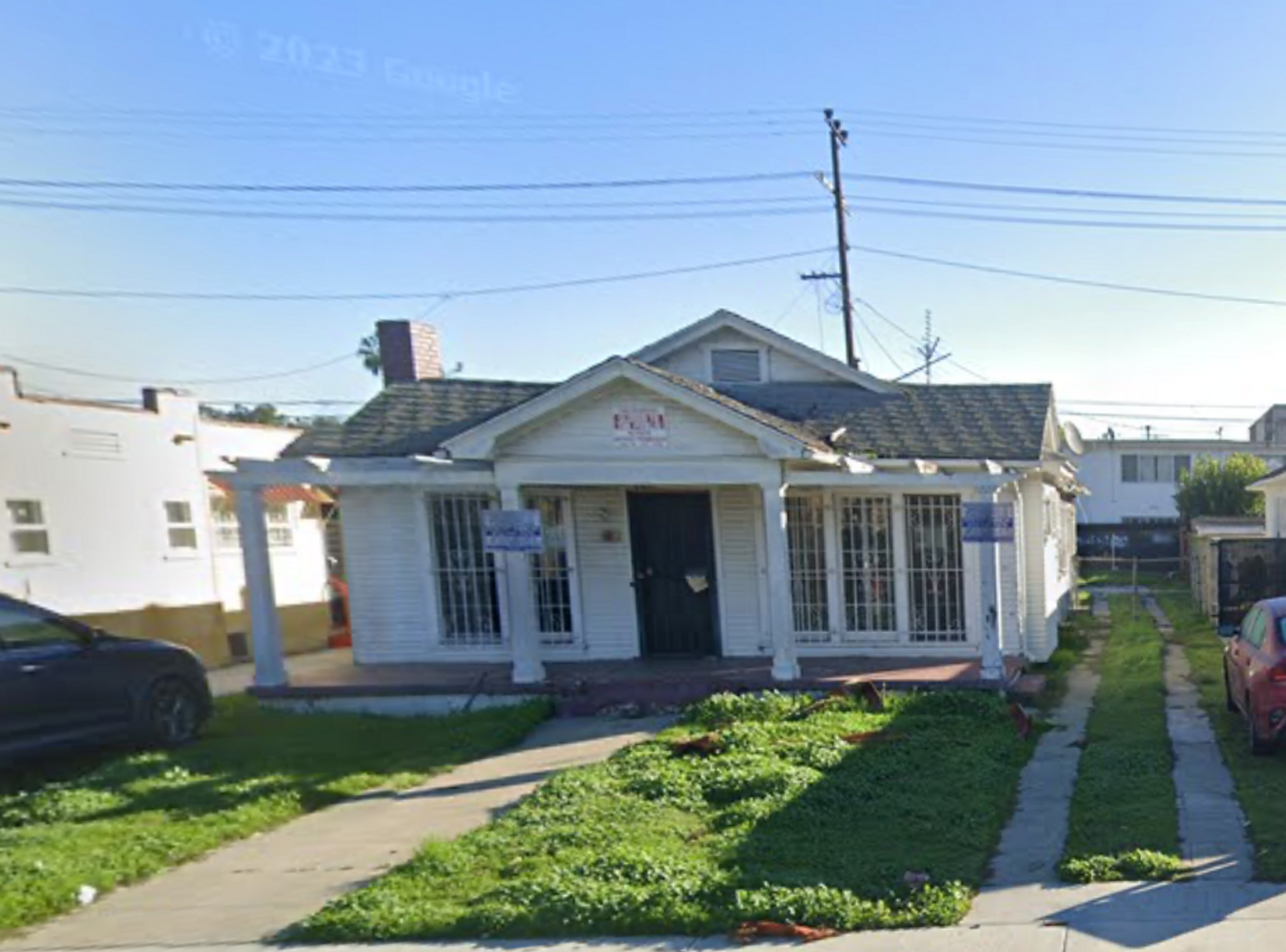 Google Street View screenshot of 5510 S. Manhattan Place, a white bungalow with a gray roof, red porch, and green lawn.