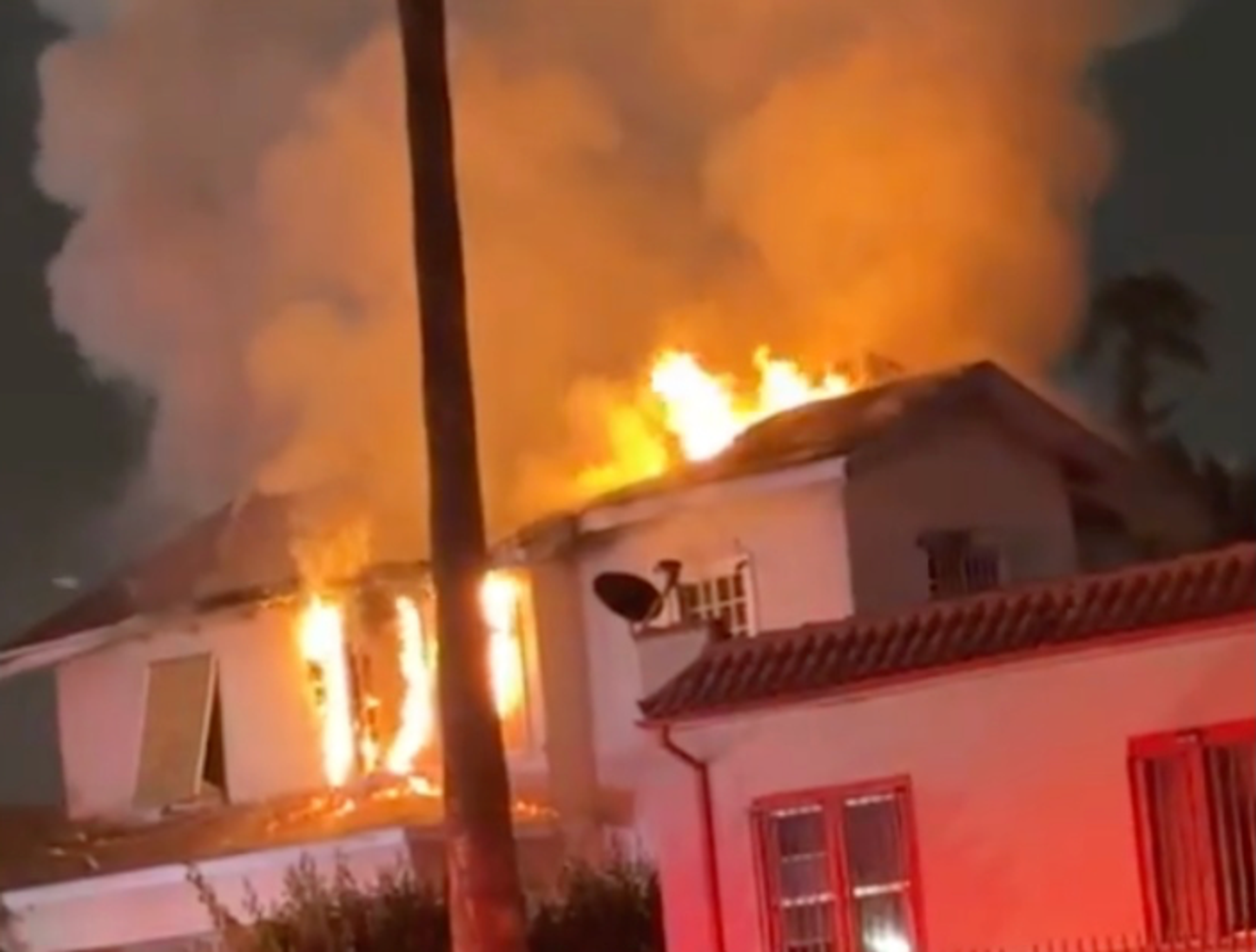 7406 S. Figueroa Street, a two-story apartment building, boarded up and on fire against the night sky.