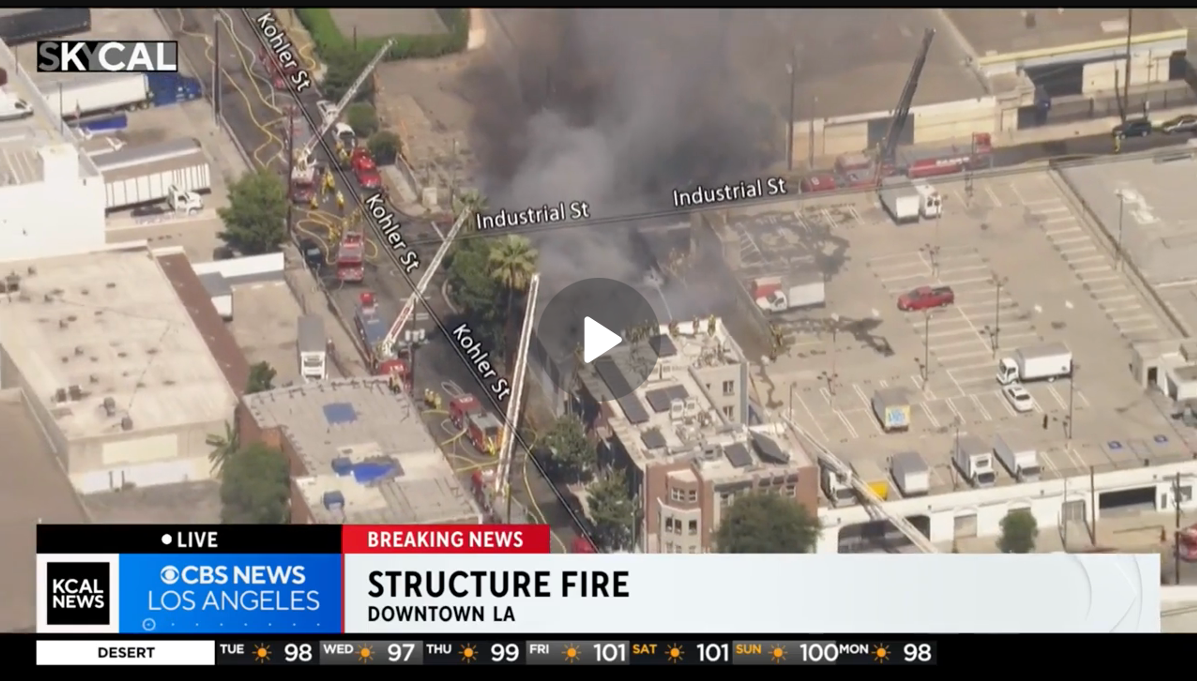 Screenshot from KCAL news report, showing 1200 Industrial Street on fire, with the fire being fought from the roof of the Olympia Hotel SRO next door.