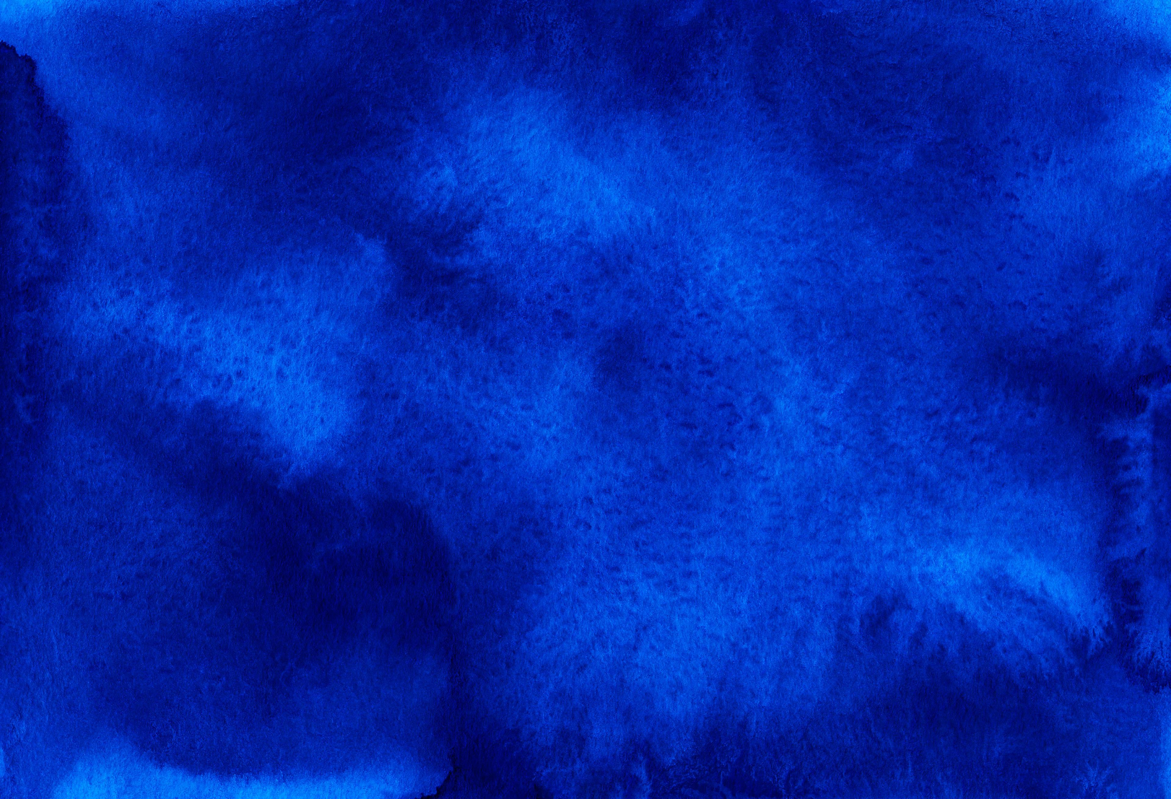 Abstract watercolor wash in deep cobalt blue with mottled lighter patches on textured paper.