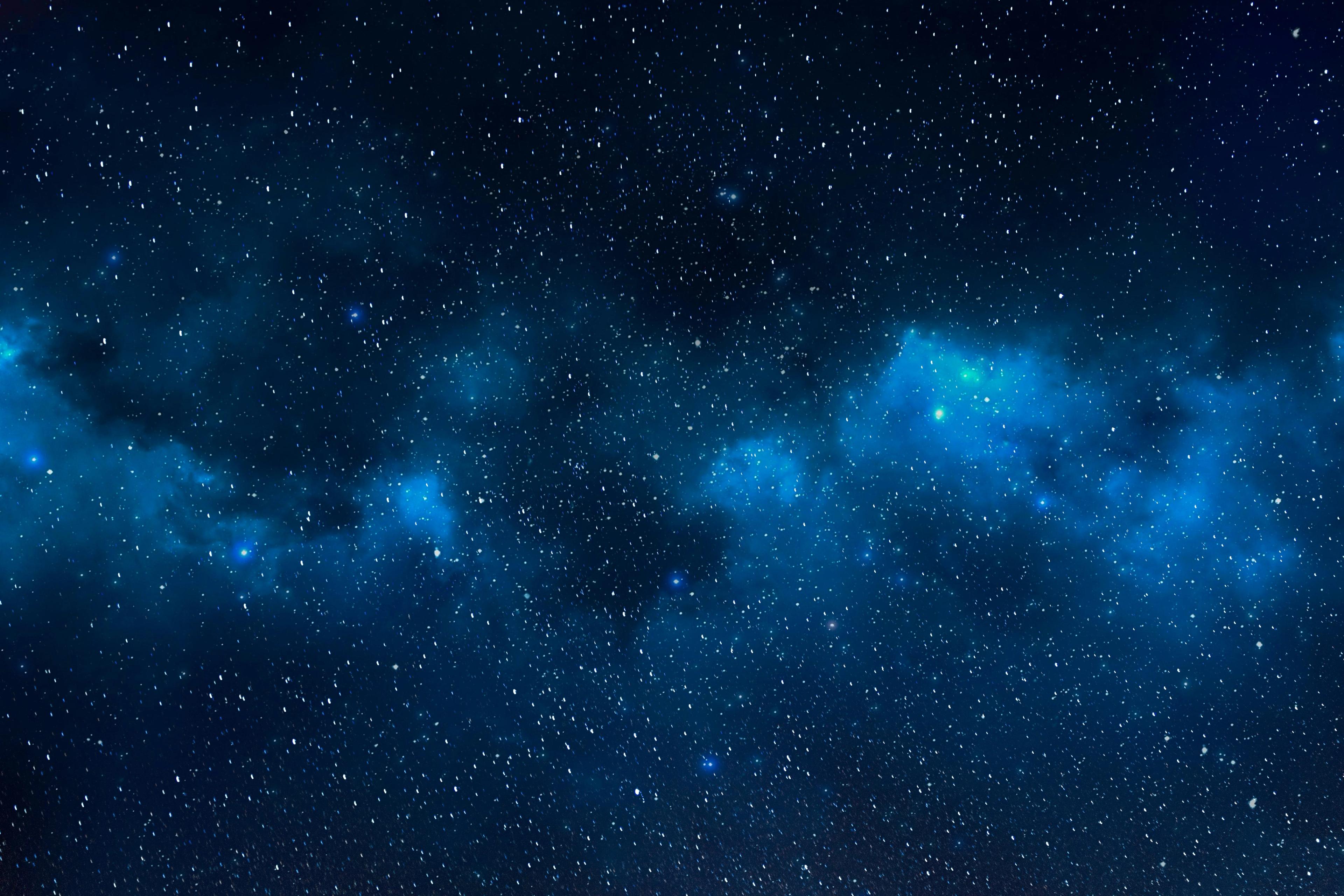 A star-filled night sky with patches of glowing blue nebula clouds against deep darkness.