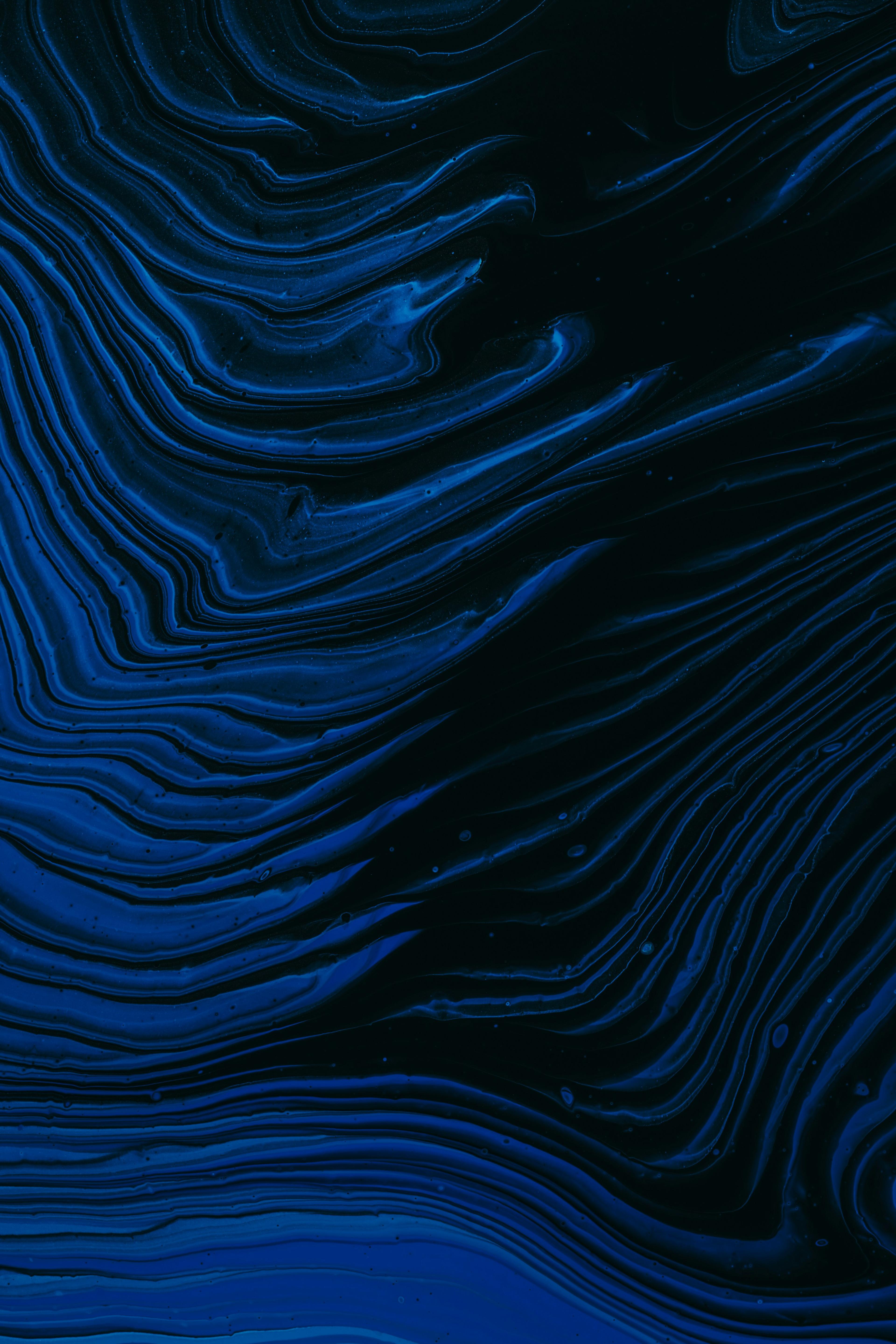Abstract acrylic pour with wavy blue and black bands forming a rippled, contour-like pattern.