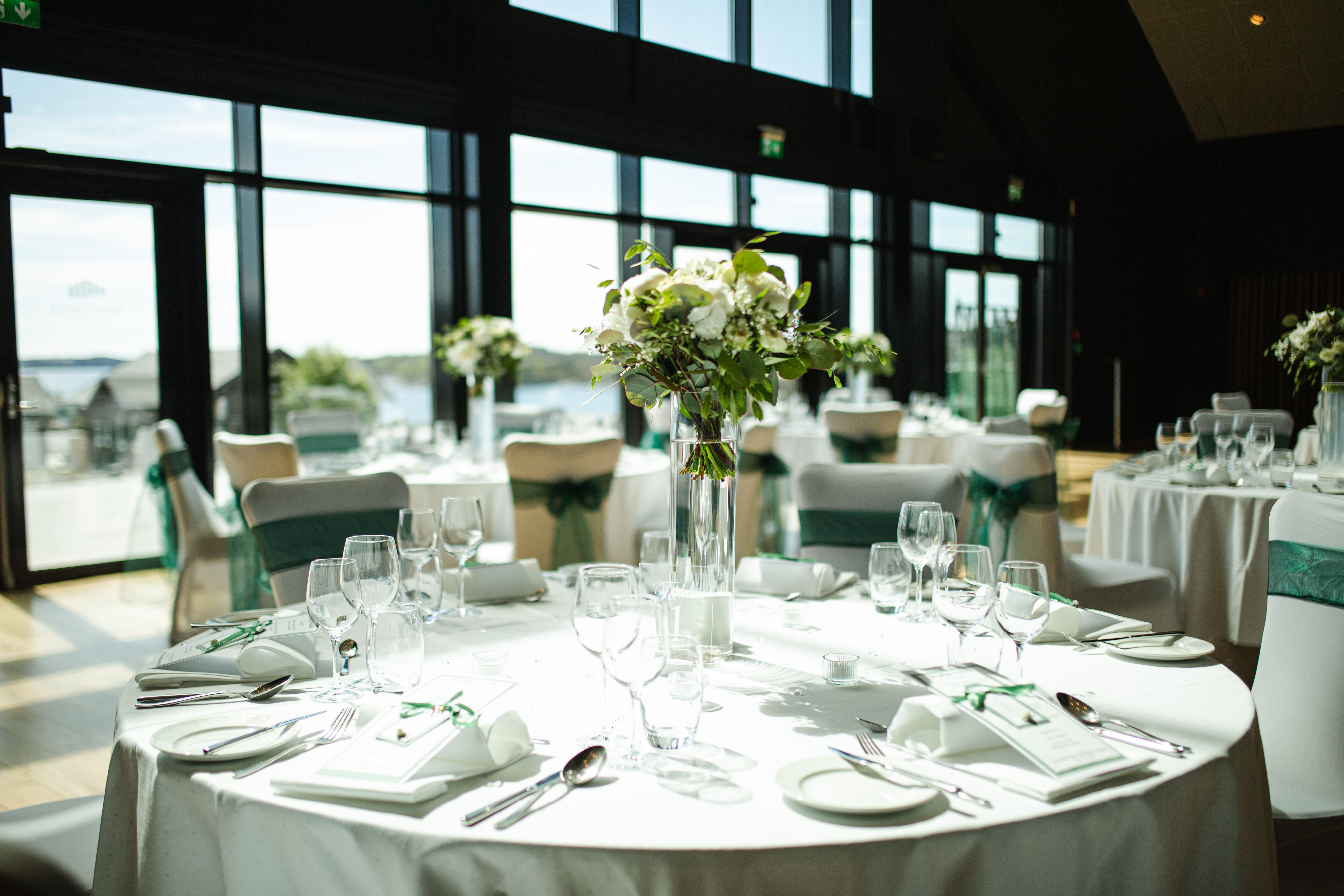 Pyntet rundt bord til bryllup med grønne detaljer