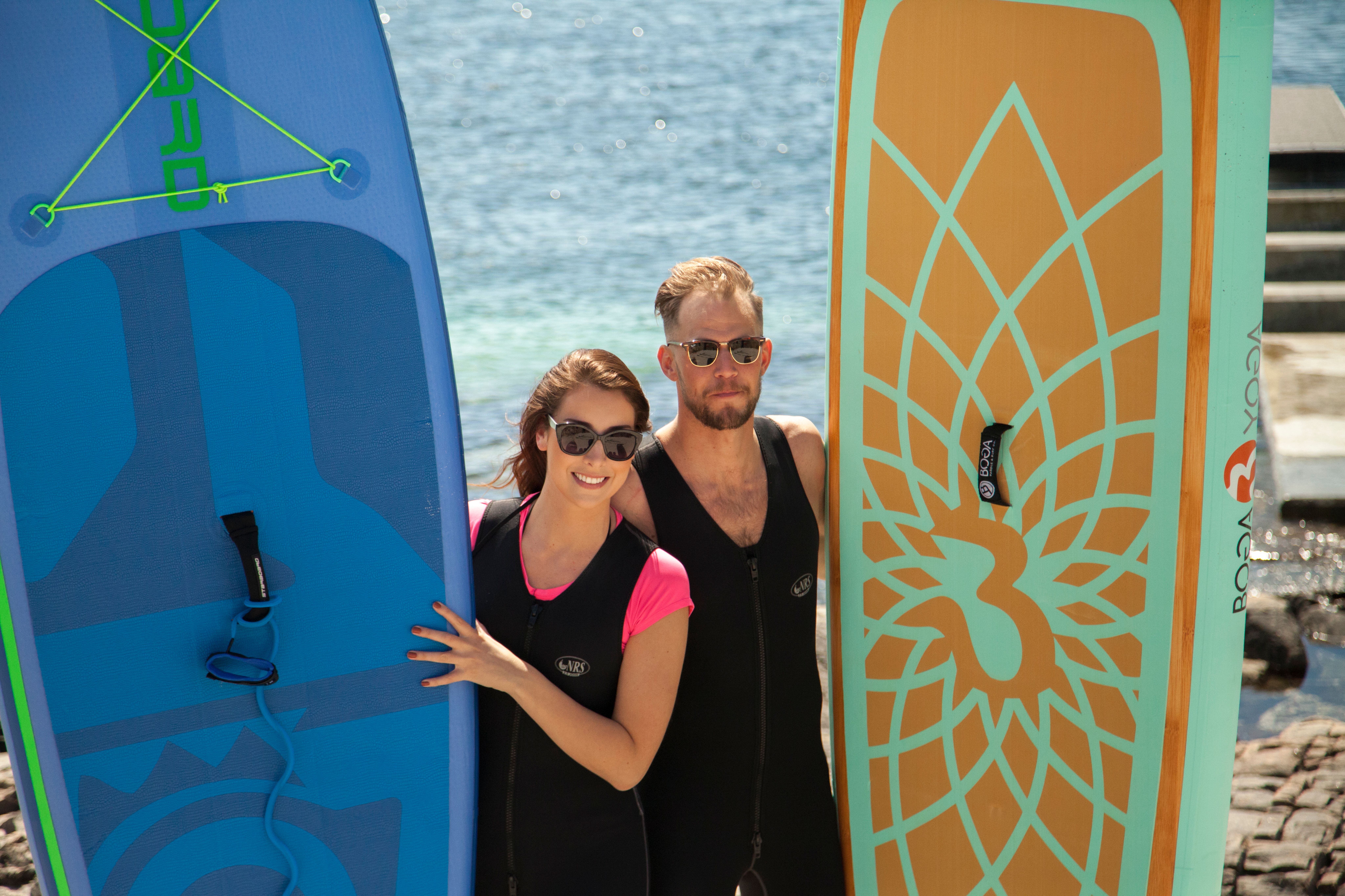 A young couple posing with SUP boards at the beach on Panorama hotel