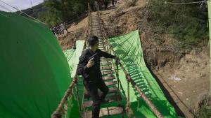 The Ultimate Guide to VFX for Gaming: From Explosions to Environments 3 Magic Media VFX, A man holding a pistol crosses a rope bridge on a film set with green screens below. Crew members are in the background.