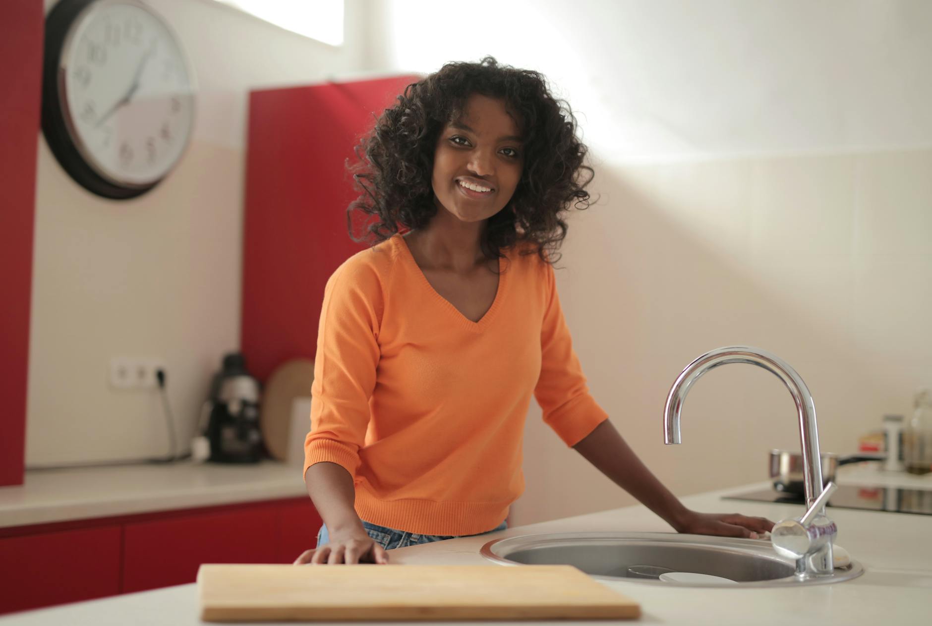 Smiling woman standing by the sink in a modern kitchen interior.