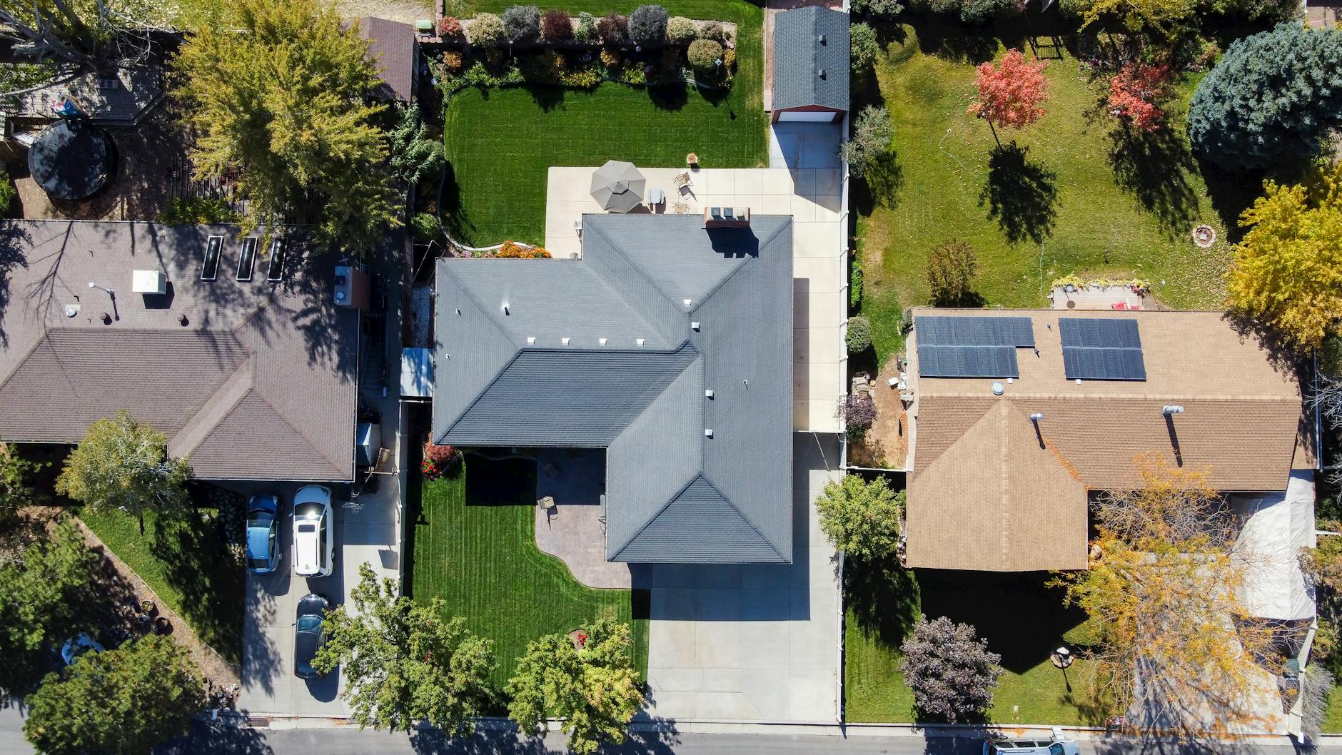 Drone shot capturing rooftops, solar panels, and green lawns in South Jordan, Utah.