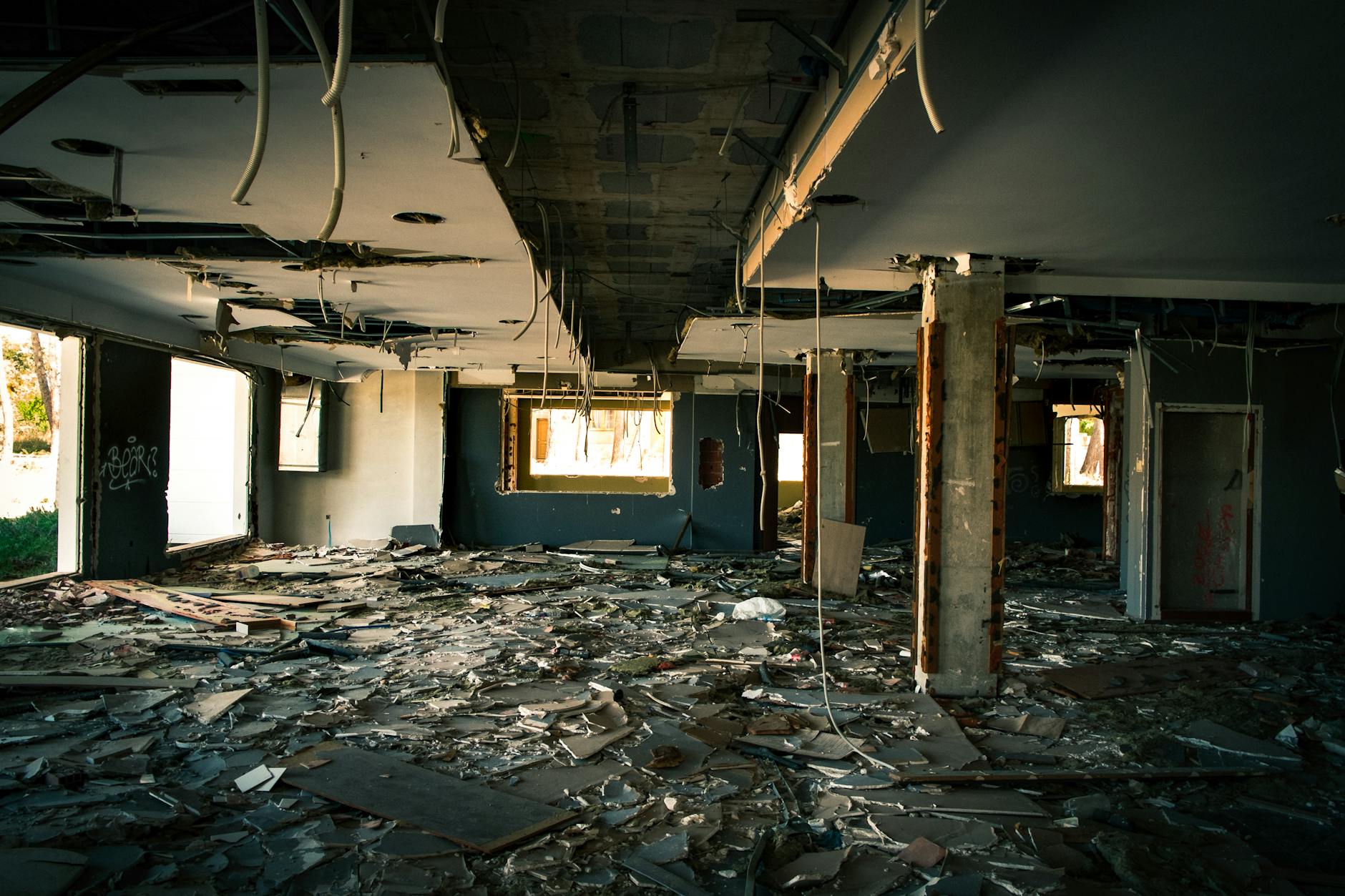 Interior of a decaying, abandoned building with debris strewn across the floor.