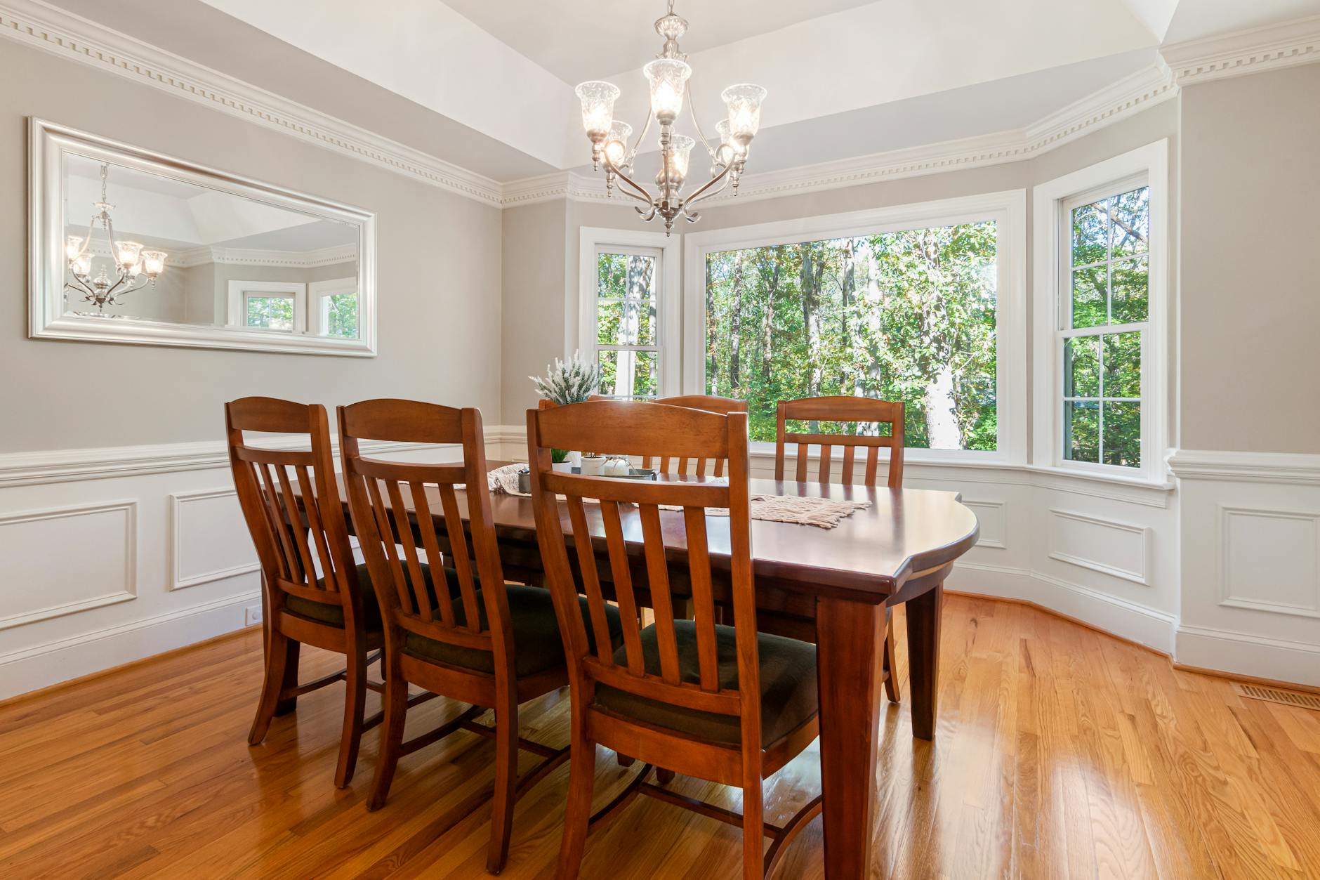 Spacious contemporary dining room featuring wooden chairs and table with bright windows.