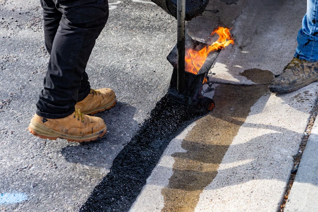 Workers applying hot asphalt with a torch