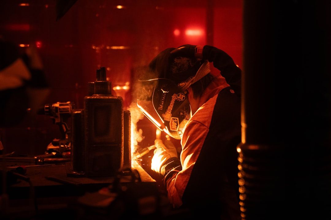 A man is welding in a dark room