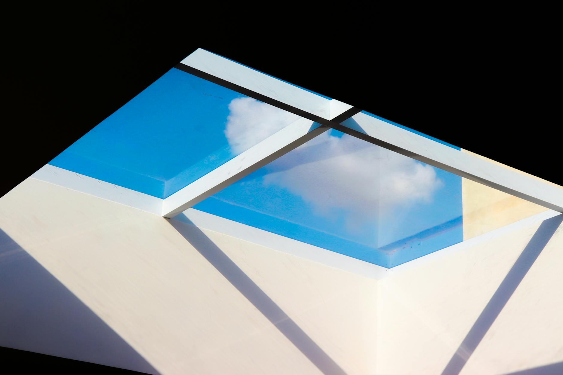 A contemporary skylight offers a view of blue skies and clouds from a modern building.
