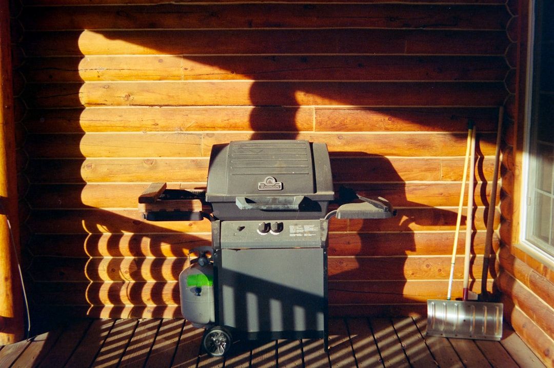 A grill sits on a wooden porch with shadows.