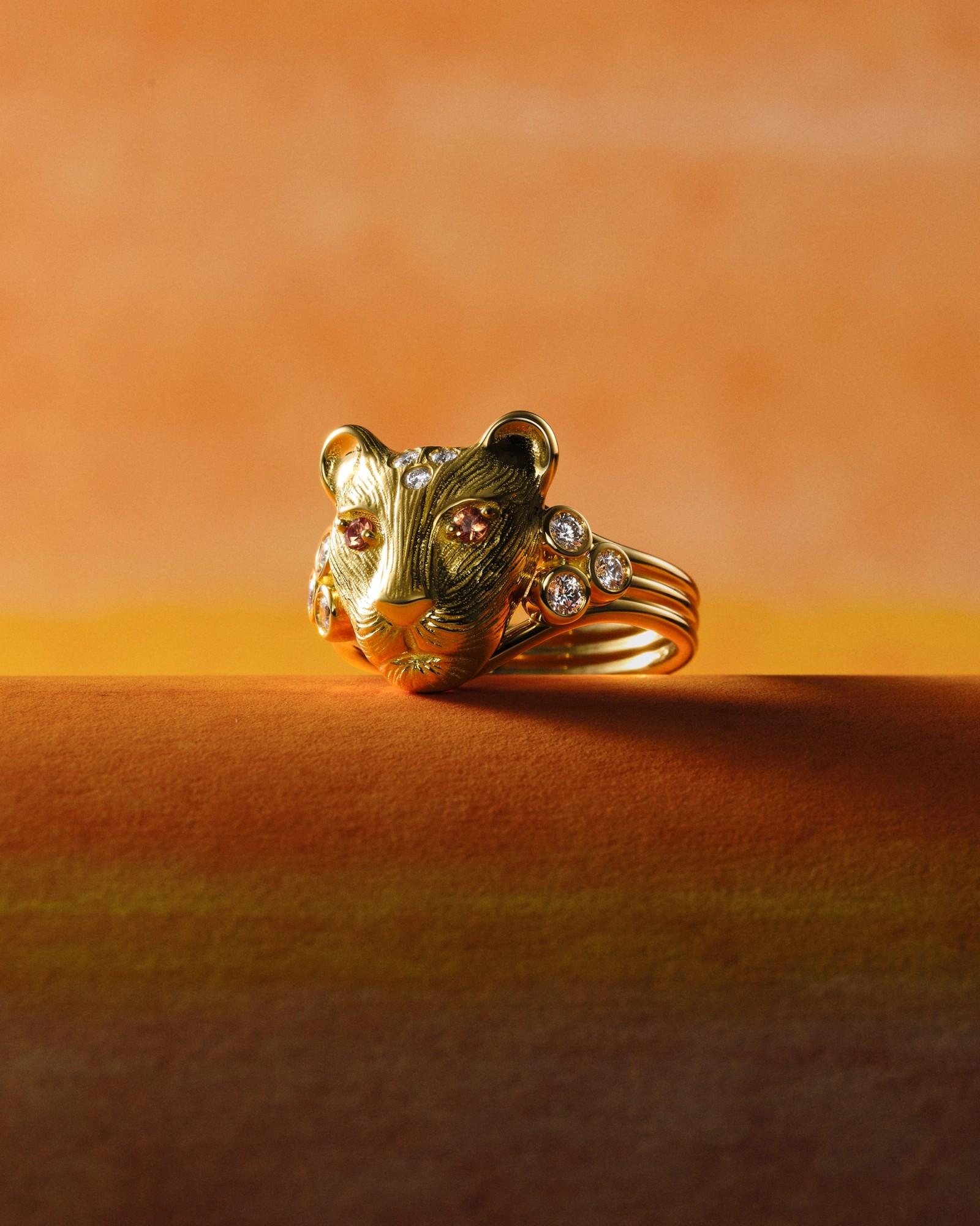 Textured gold leopard head ring with brown gem eyes, diamond accents, and multiple gold bands.