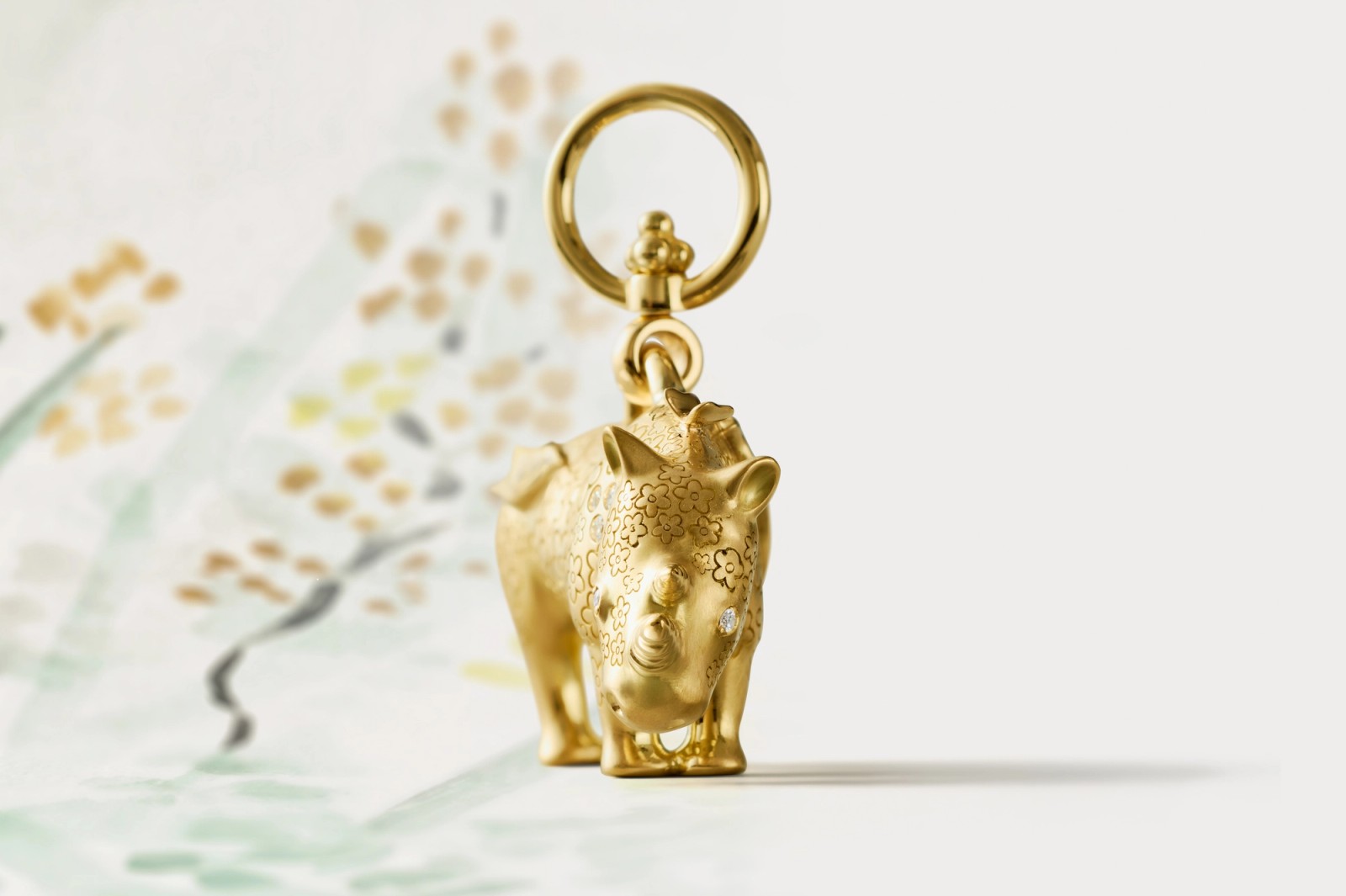 Golden rhino charm with a diamond eye, intricate patterns, and a top ring.
