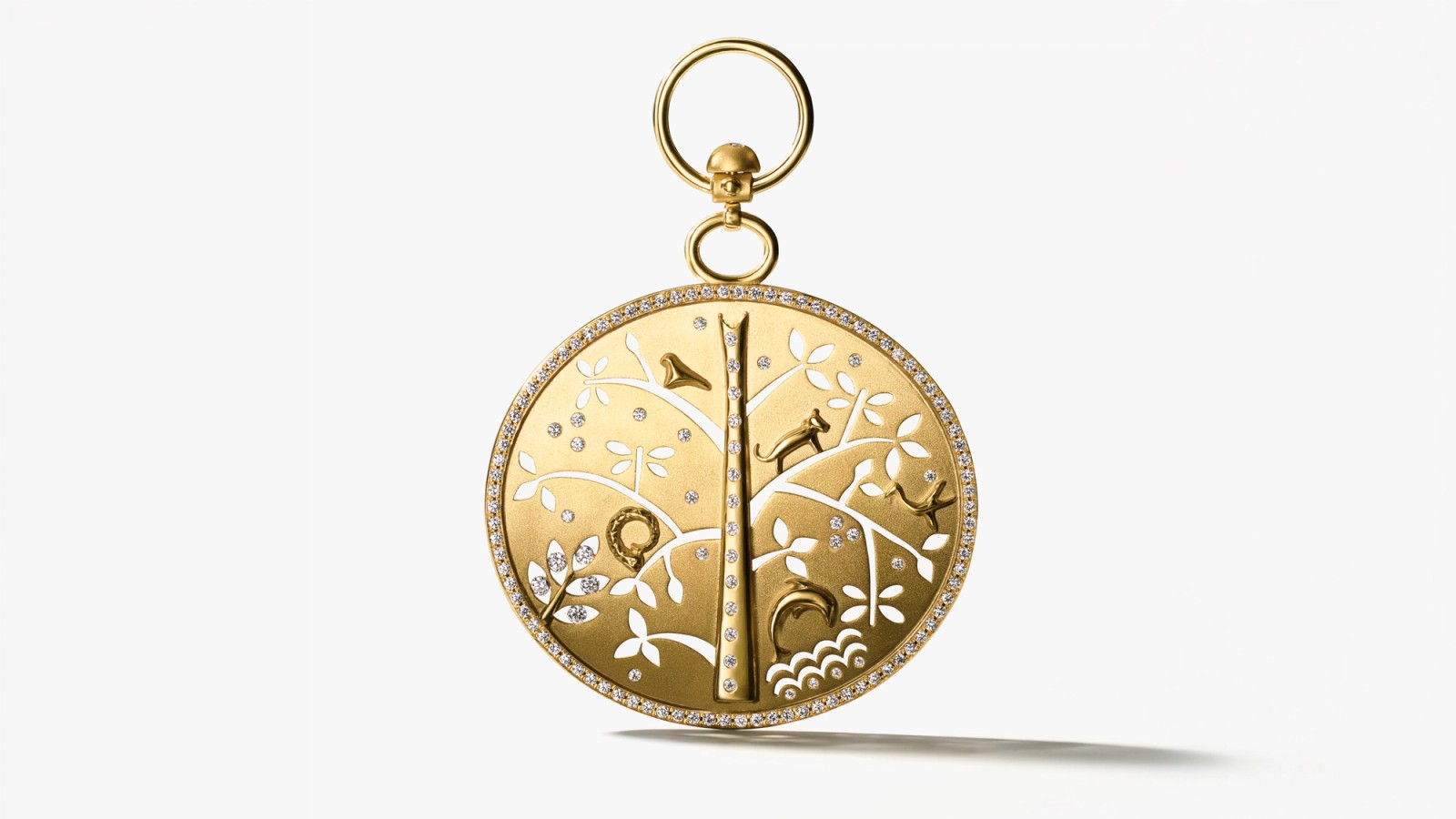 Intricate gold round pendant with tree and animal designs and diamonds.