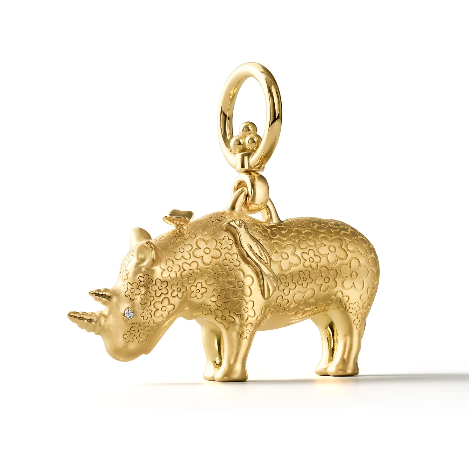A gold rhinoceros charm with floral engraving, a diamond on its horn, a bird on its back, and a butterfly on its ear.