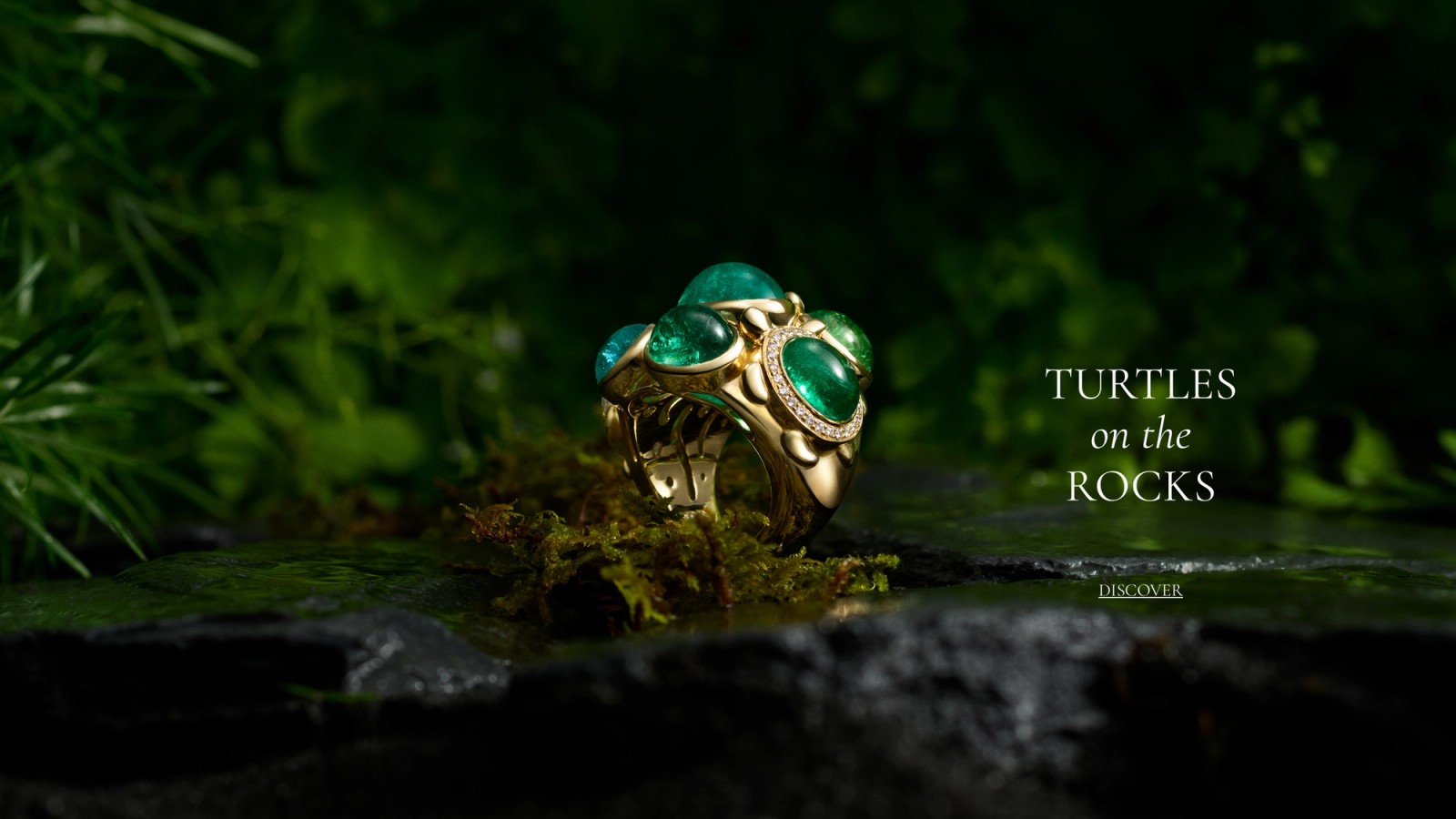Gold ring with green emeralds and diamonds, designed as turtles, on mossy rocks. Text: 'TURTLES on the ROCKS'.