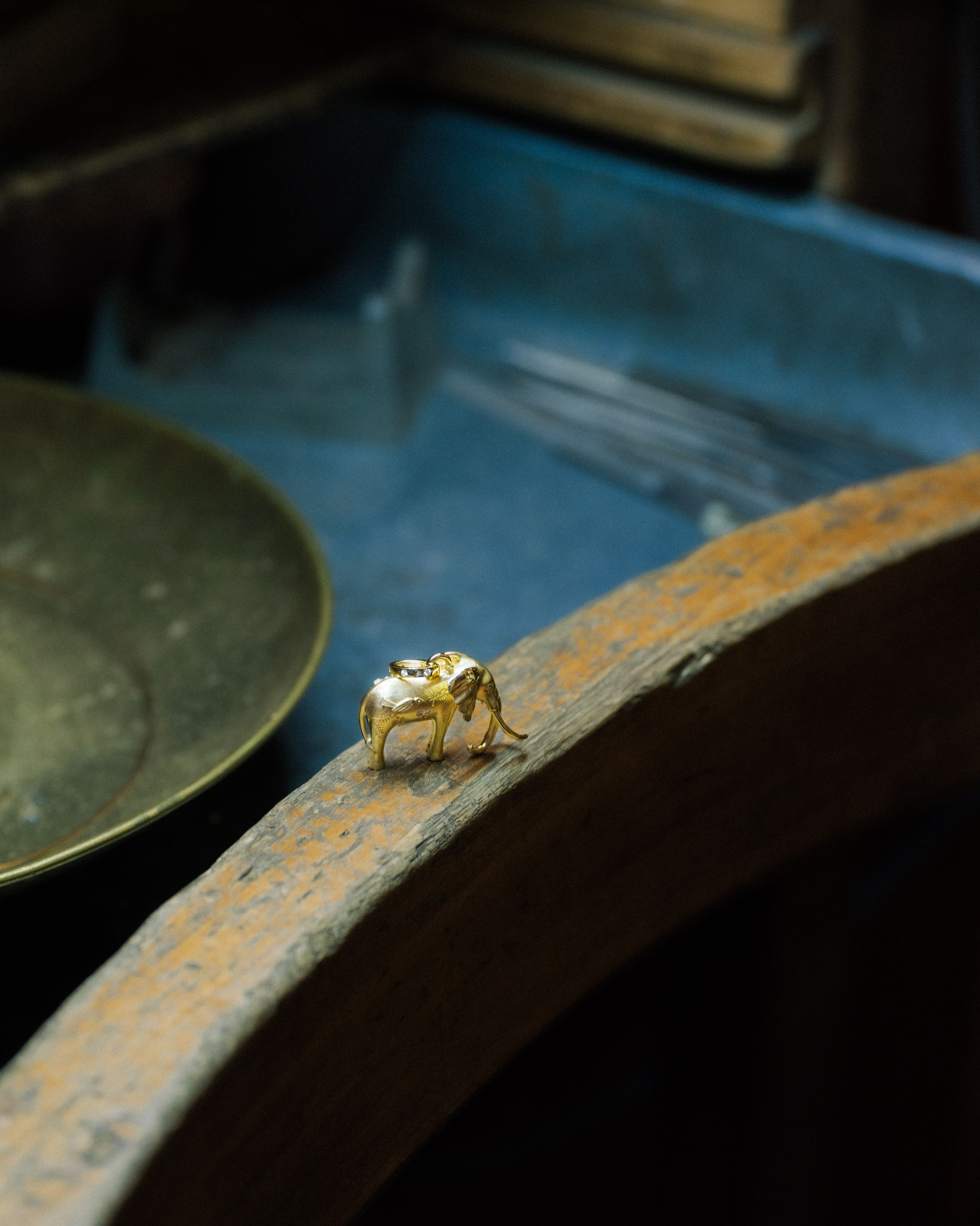 A small golden elephant figurine rests on a rustic wooden surface.