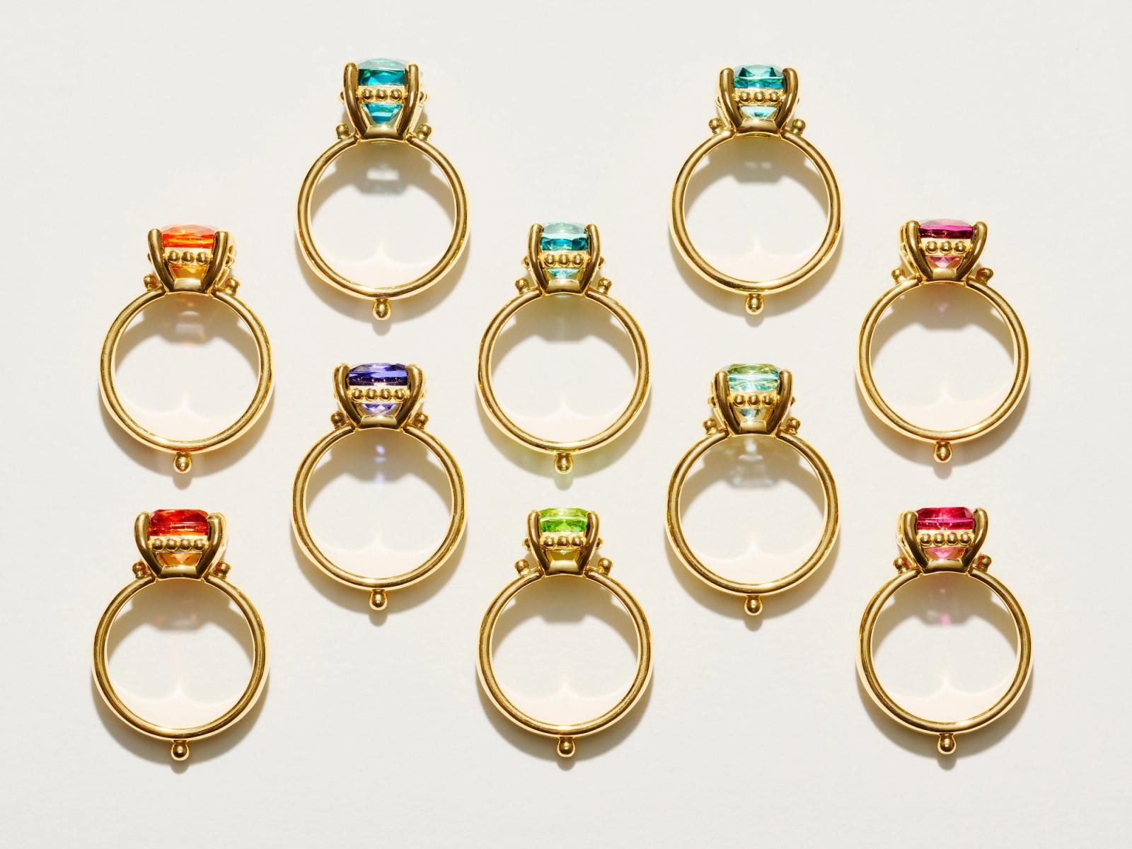 Assortment of colorful faceted gemstones in various shapes on a white background.