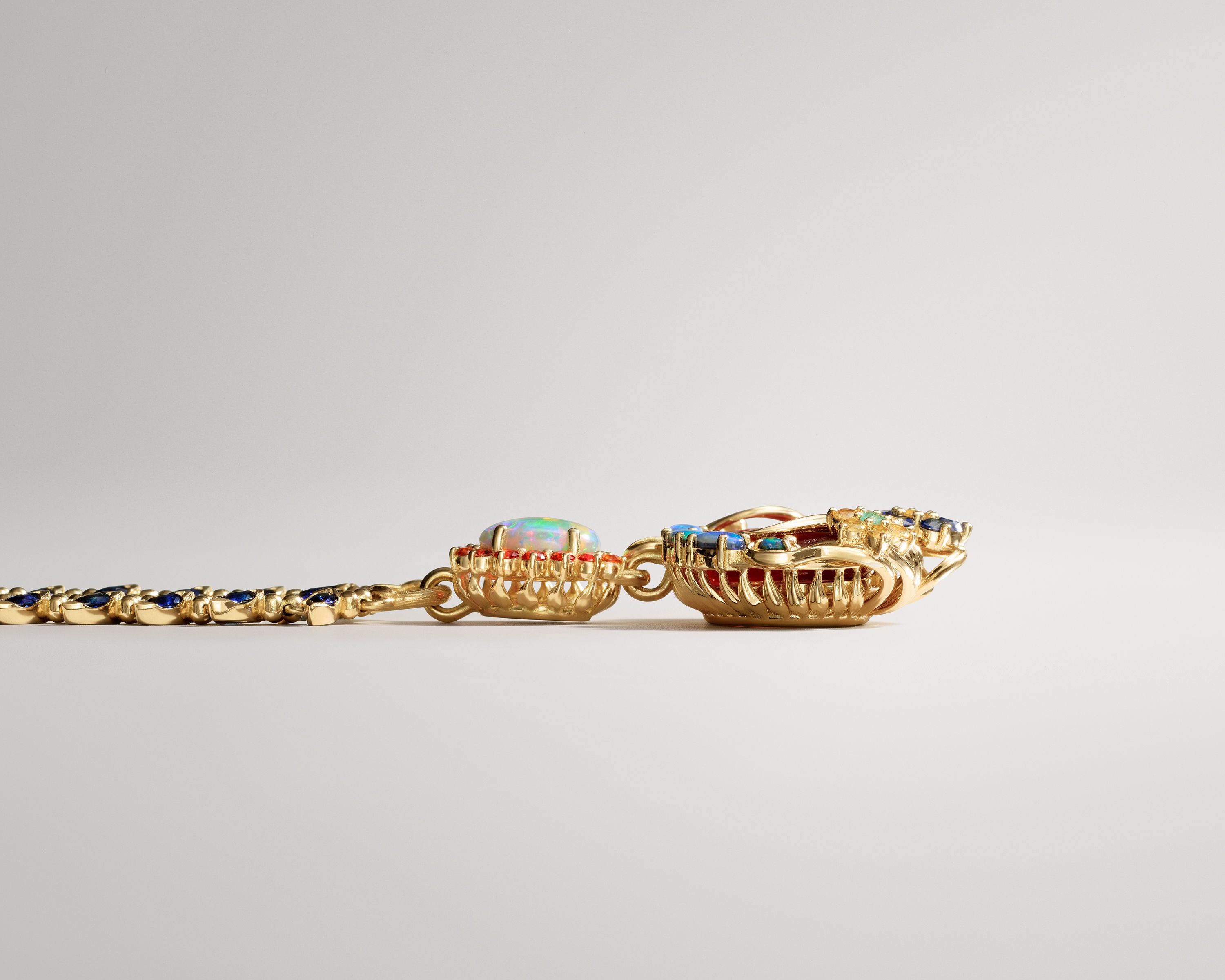 Ornate gold jewelry featuring an opal, red and blue gemstones, and a multi-colored pendant.