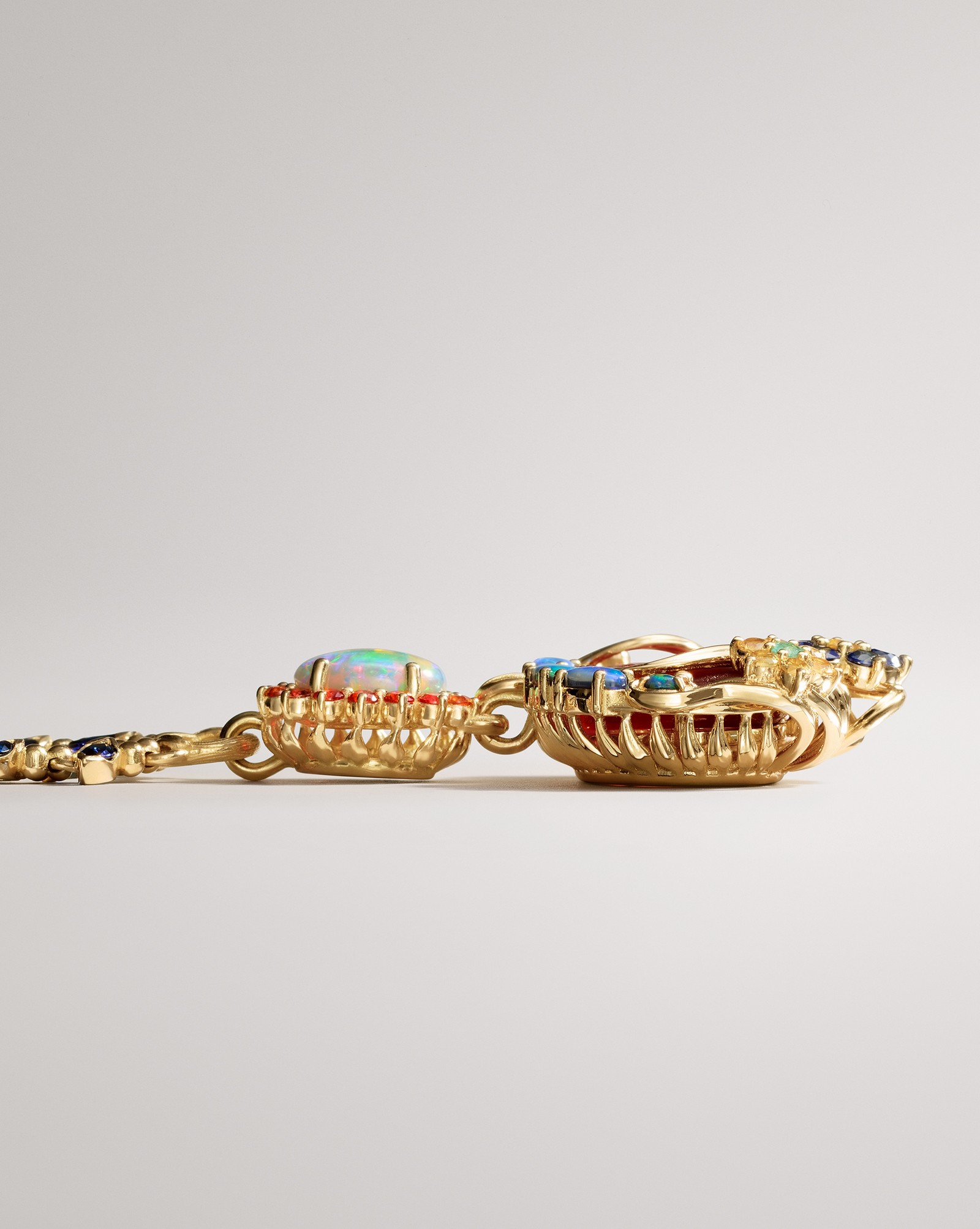 Ornate gold jewelry featuring an opal, red and blue gemstones, and a multi-colored pendant.